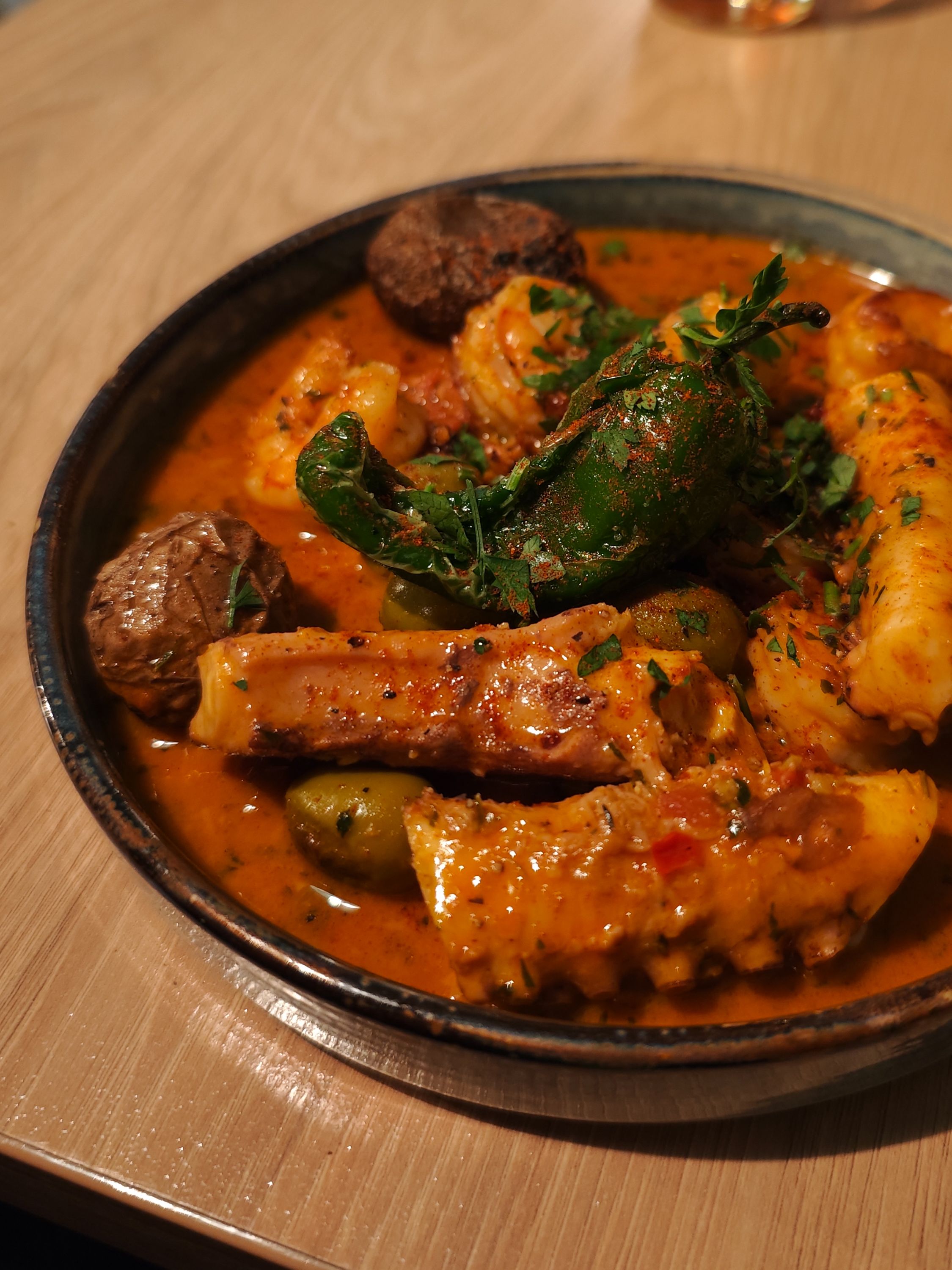 Spiced curry dish with herbs and sauce in wooden bowl, restaurant food photography Wroclaw Poland