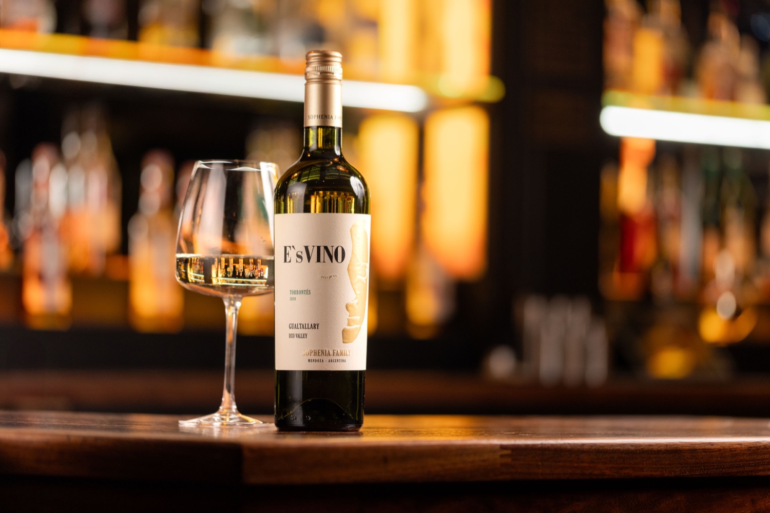 Bottle of Sophenia E'sVino Torrontes and a filled glass on the bar at Porters Steakhouse Southampton, with warm bottle-lit shelving behind, drinks photography by Ryan Stanikk