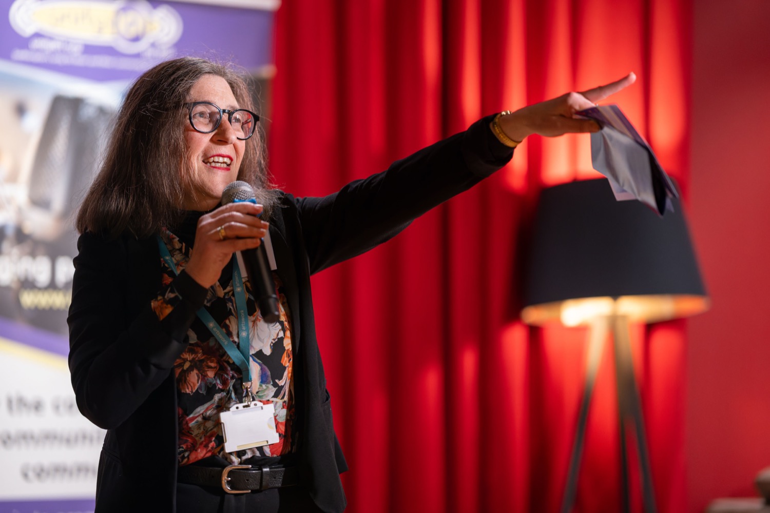 Speaker presenting with microphone and gesturing to audience at City Networking event at Showcase Cinemas Deluxe Southampton, corporate event photography