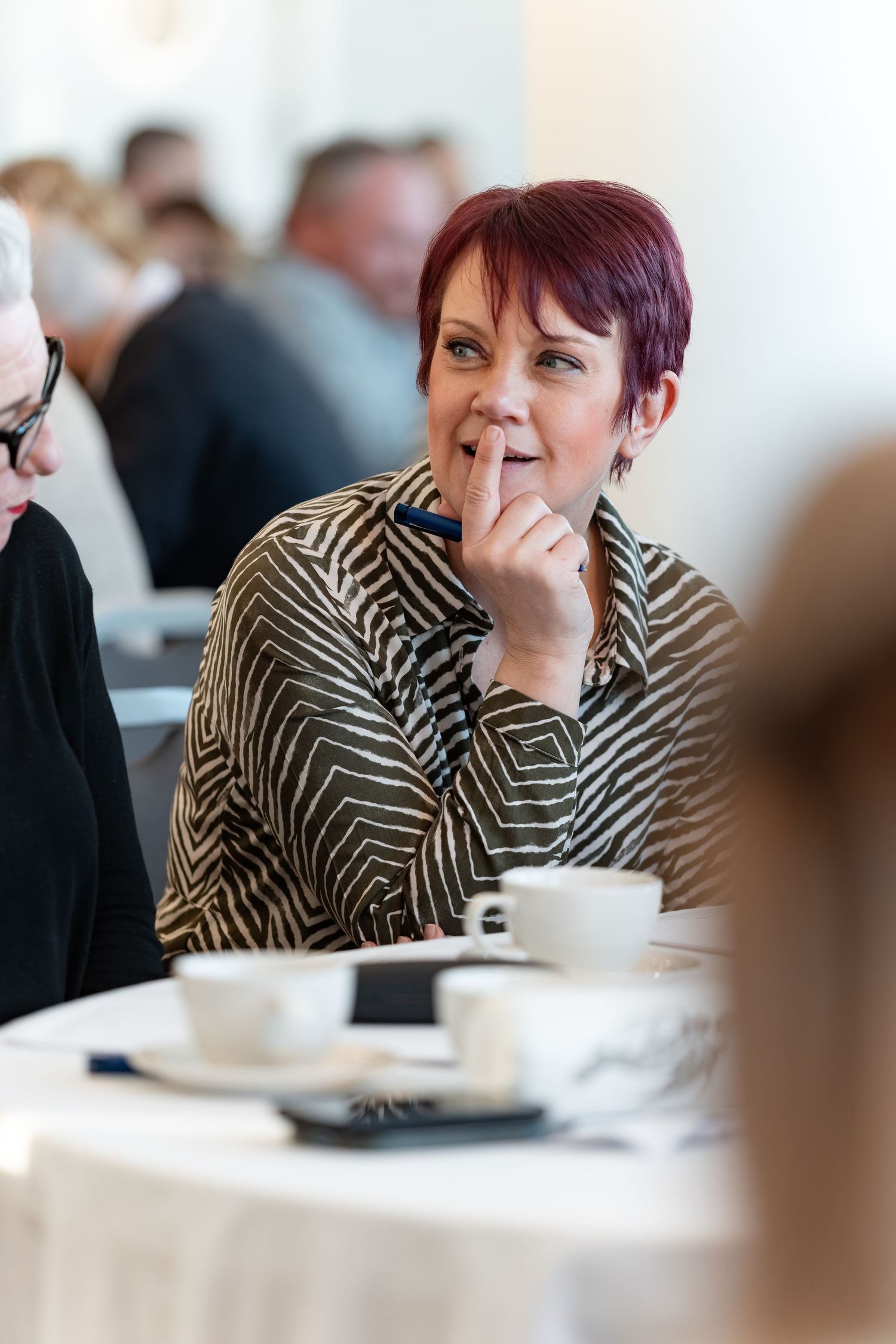 Delegate smiling thoughtfully with pen in hand during a conference session, candid corporate event photography Southampton