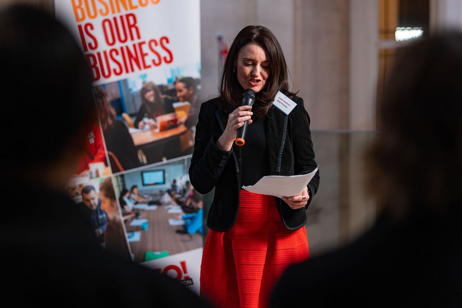 Woman speaking into a microphone at a business awards event with a branded banner behind, corporate event photography Southampton