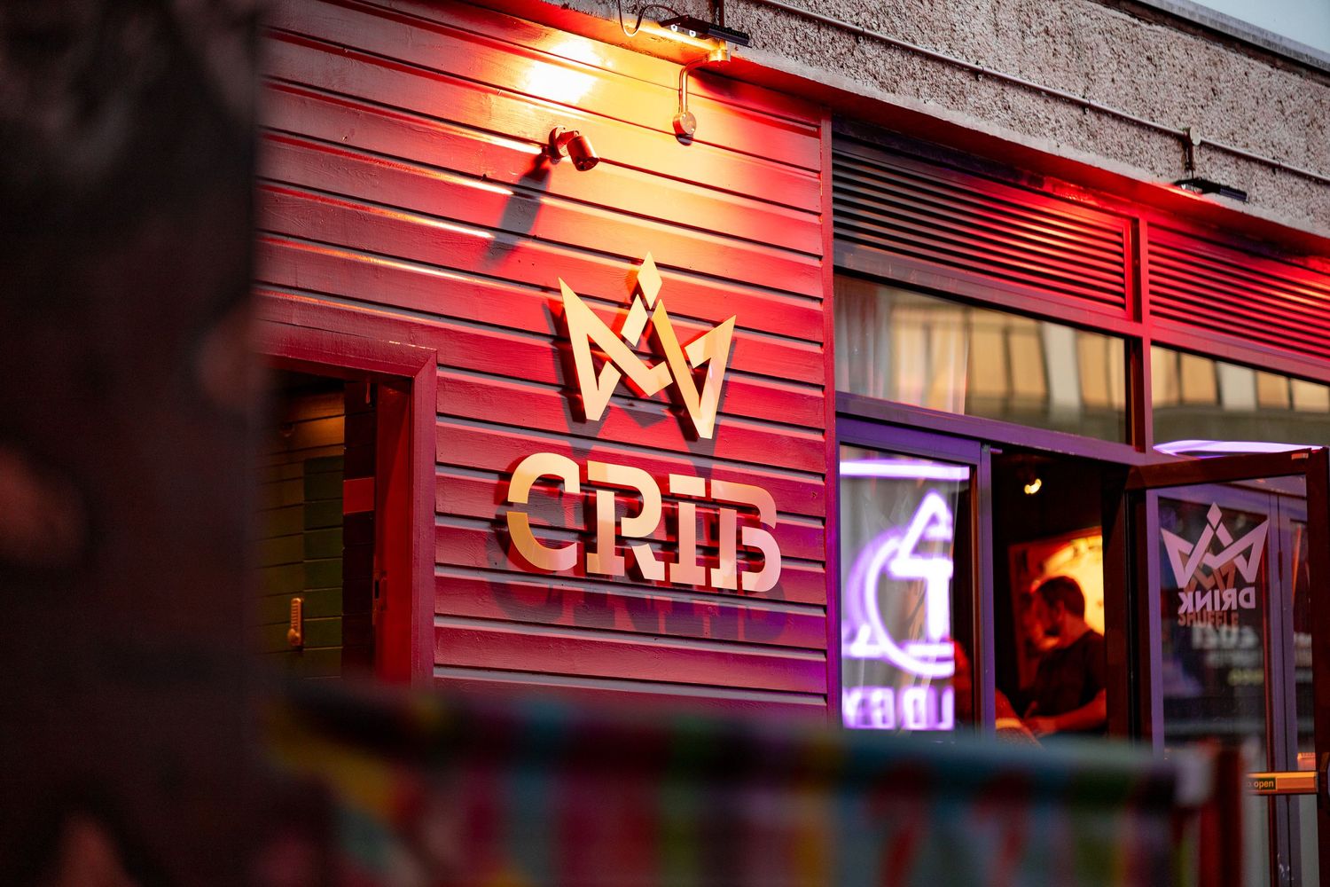 Crib venue exterior at night with red neon-lit cladding, crown logo and illuminated signage, commercial nightlife exterior photography