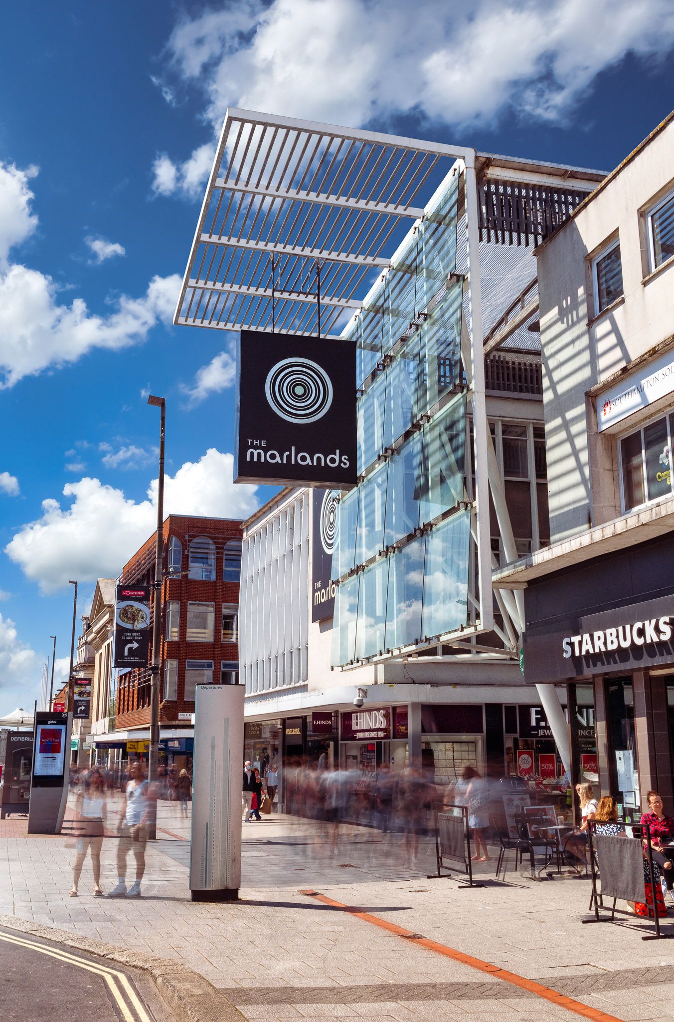 The Marlands shopping centre Southampton with modern glass and steel canopy, Starbucks and motion-blurred pedestrians, architectural exterior photography