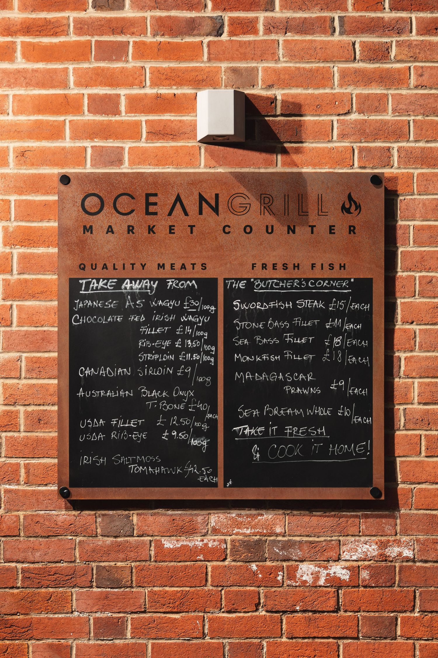 Ocean Grill Market Counter chalkboard menu on brick wall listing quality meats and fresh fish, commercial signage photography