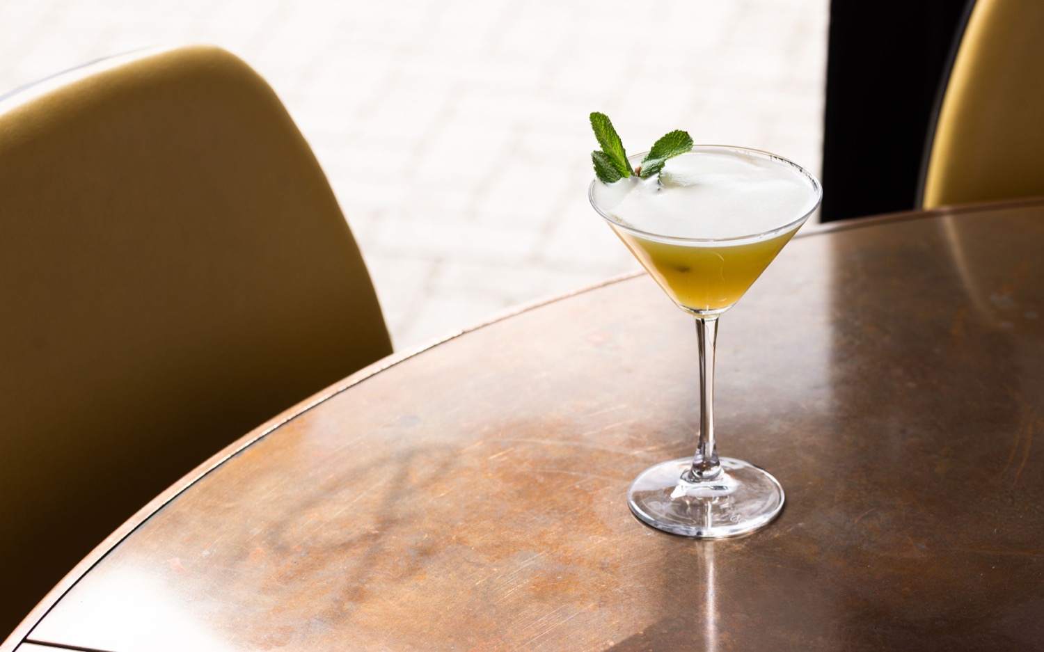 Passionfruit cocktail in a martini glass with mint garnish on a copper table at Banana Wharf Ocean Village Southampton, drink photography