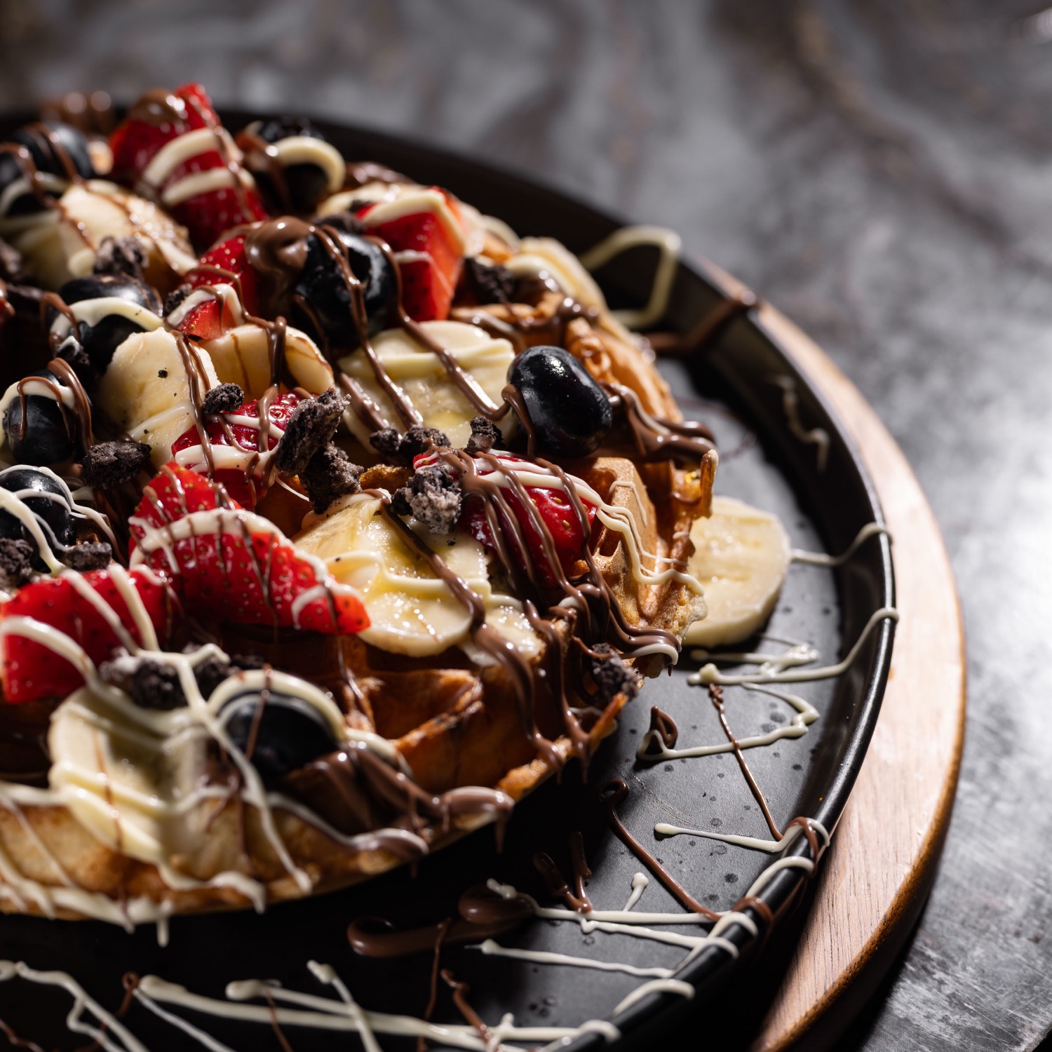 Loaded waffle with banana slices, strawberries, Oreo pieces and chocolate drizzle at Barga Eastleigh, dessert food photography