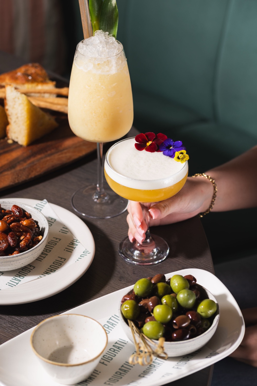 Bellini cocktail and espresso martini with edible flowers alongside olives and focaccia at Figurati Italian restaurant Southampton, food and drink photography