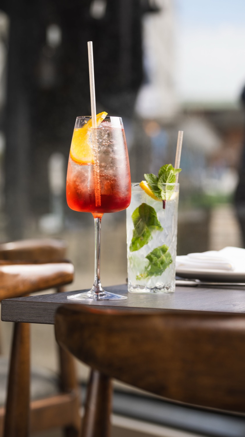 Aperol spritz and mojito cocktails on an outdoor terrace table at Figurati Italian restaurant Southampton, summer drink photography
