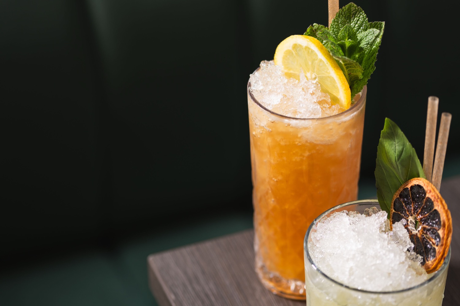 Two crushed ice cocktails with lemon, mint and dried orange garnish on a dark table at Figurati Italian restaurant Southampton, drink photography
