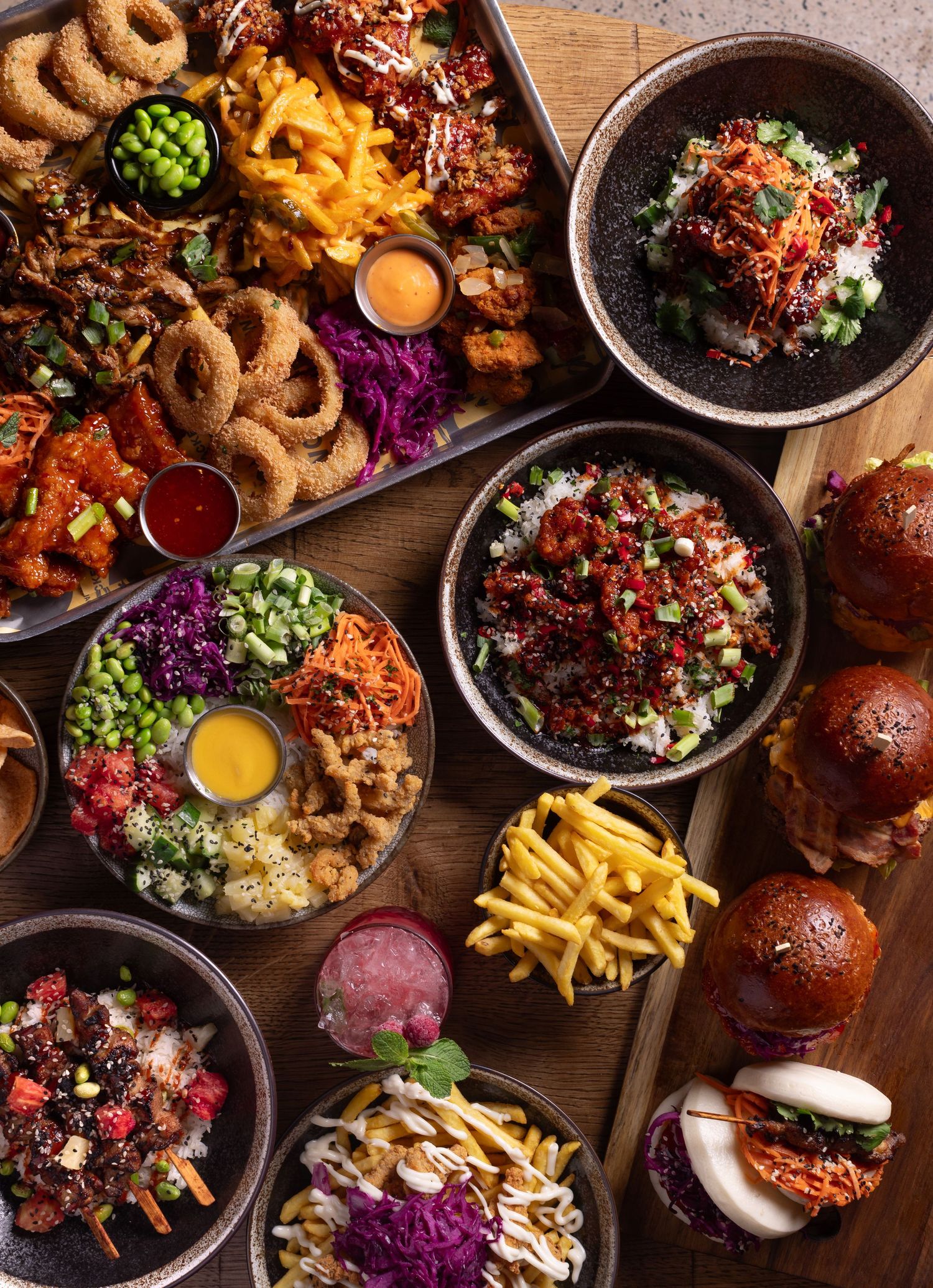 Overhead shot of a Korean and Asian fusion food spread with poke bowls, fried chicken, sliders, onion rings and fries, Asian restaurant food photography Southampton