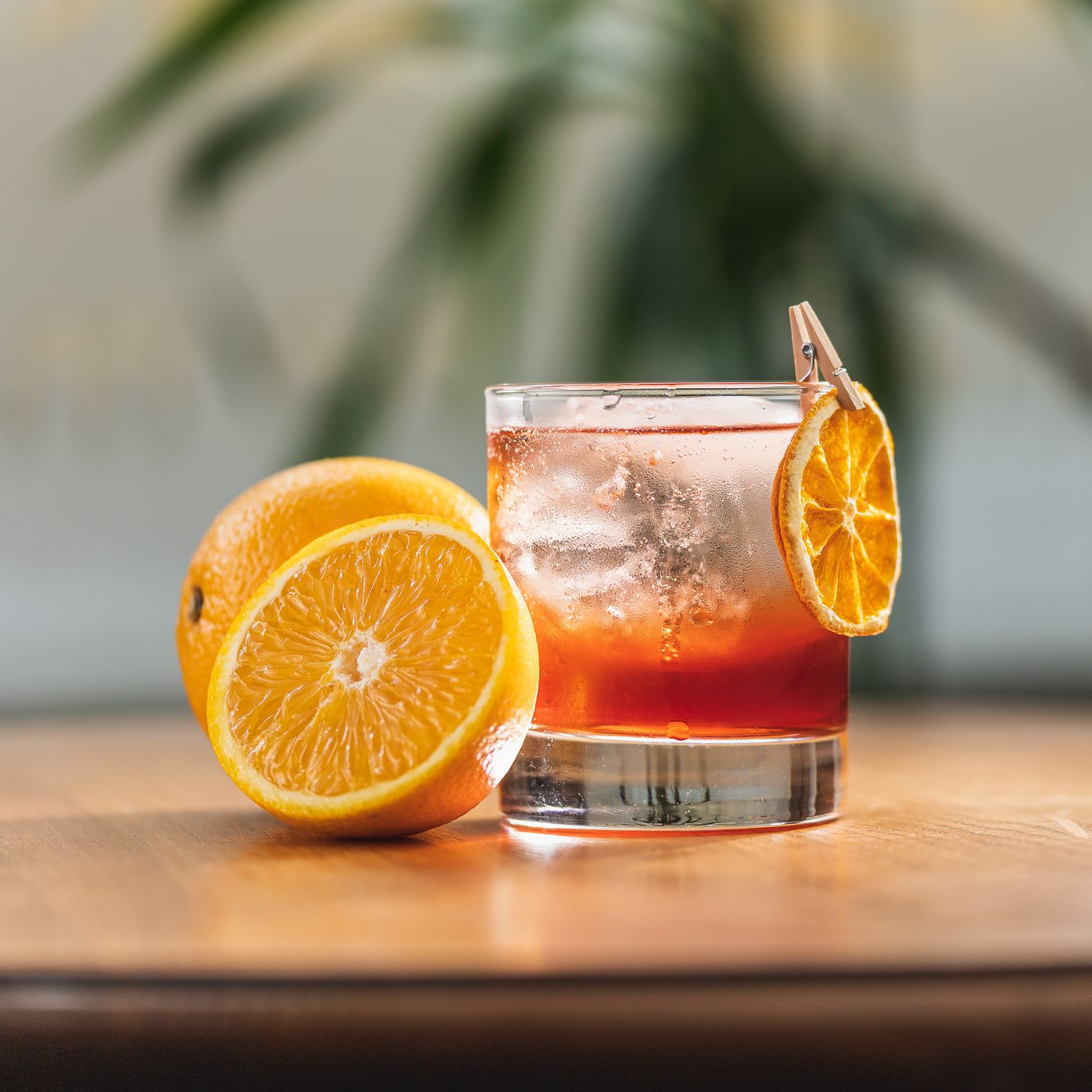 Negroni style cocktail in a rocks glass with ice and a dried orange garnish alongside a fresh halved orange at Mango restaurant Southampton, cocktail photography