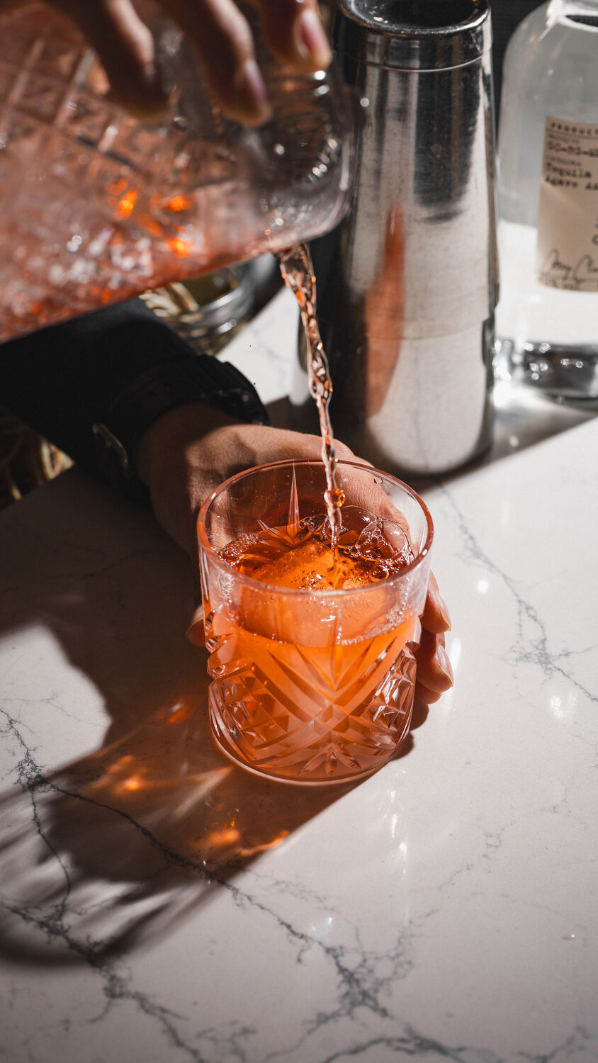 Cocktail being poured over cut ice on a marble bar at Mestizo Mexican restaurant, King's Road Chelsea, London drink photography