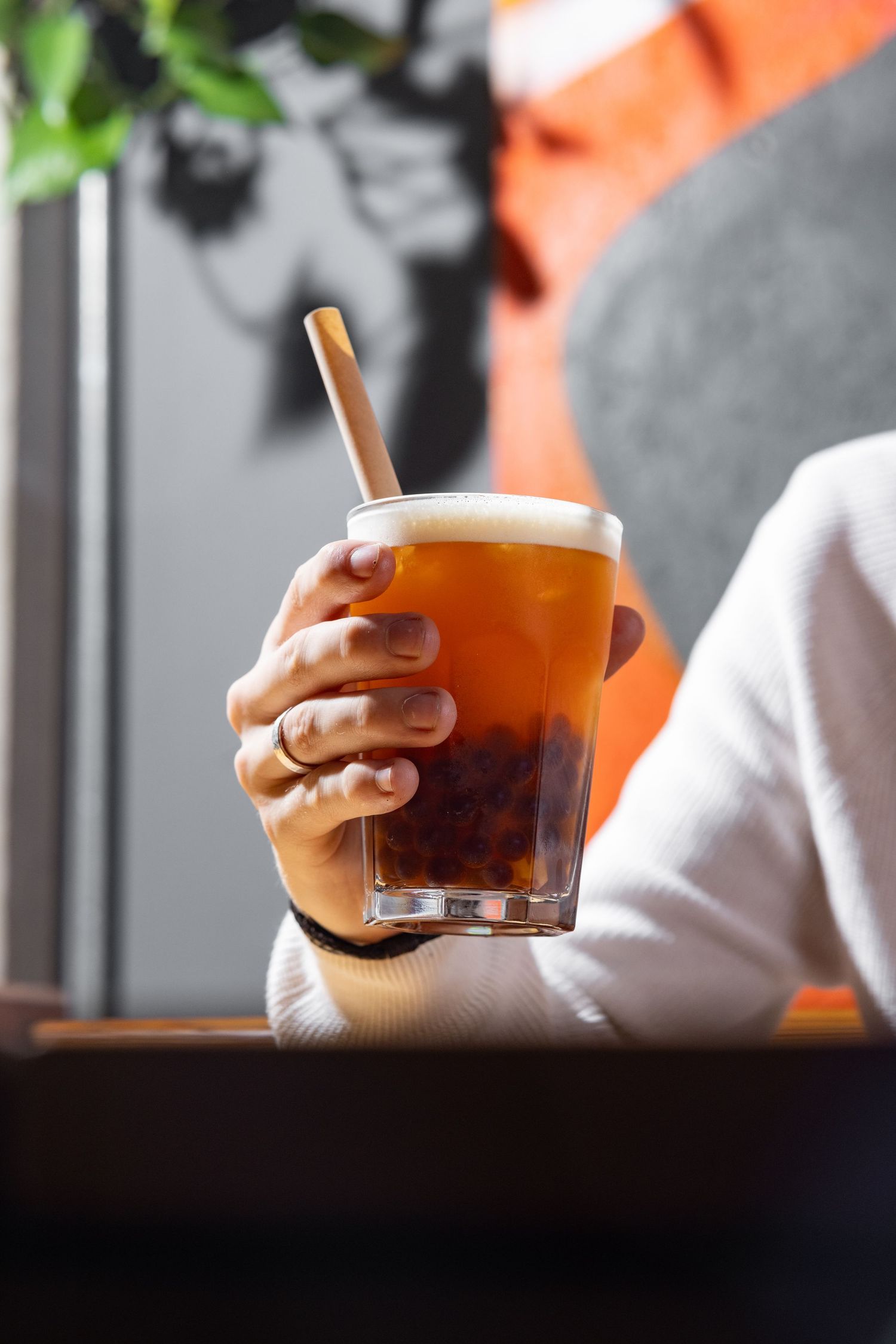 Hand holding a bubble tea with tapioca pearls and a bamboo straw at Mettricks cafe Southampton, drink photography