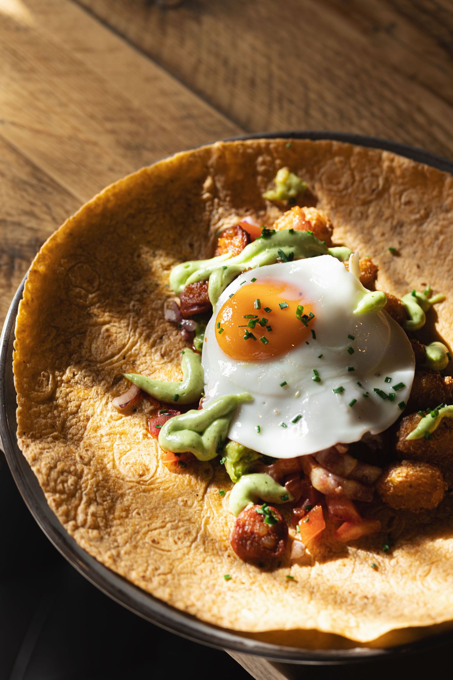Fried egg on a breakfast hash with chorizo, potatoes and avocado sauce in a rustic bowl at Mettricks Portswood Southampton, brunch food photography