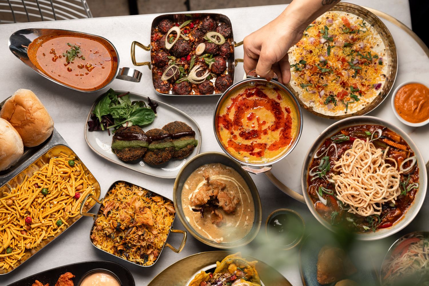 Overhead flat-lay of Indian curries, biryani, kebabs, naan, pav buns and sides at Padharo restaurant Southampton, Indian food photography
