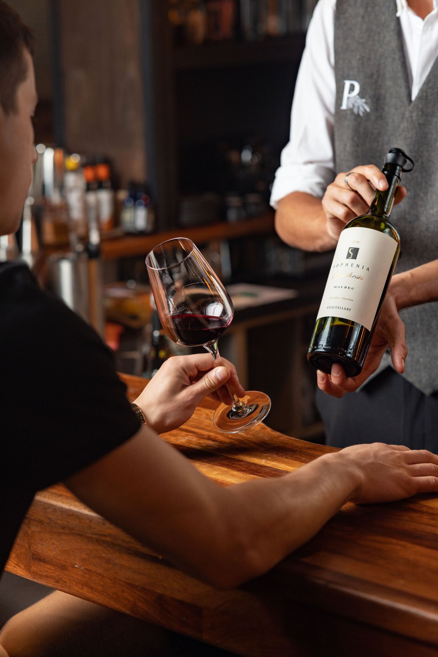 Bartender presenting a bottle of Sophenia Malbec red wine to a guest holding a glass at Porters bar Southampton, restaurant and hospitality drink photography