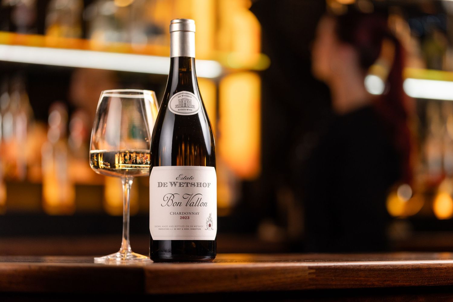 De Wetshof Bon Vallon Chardonnay wine bottle and glass on a bar counter with warm bokeh lighting at Porters Southampton, wine photography