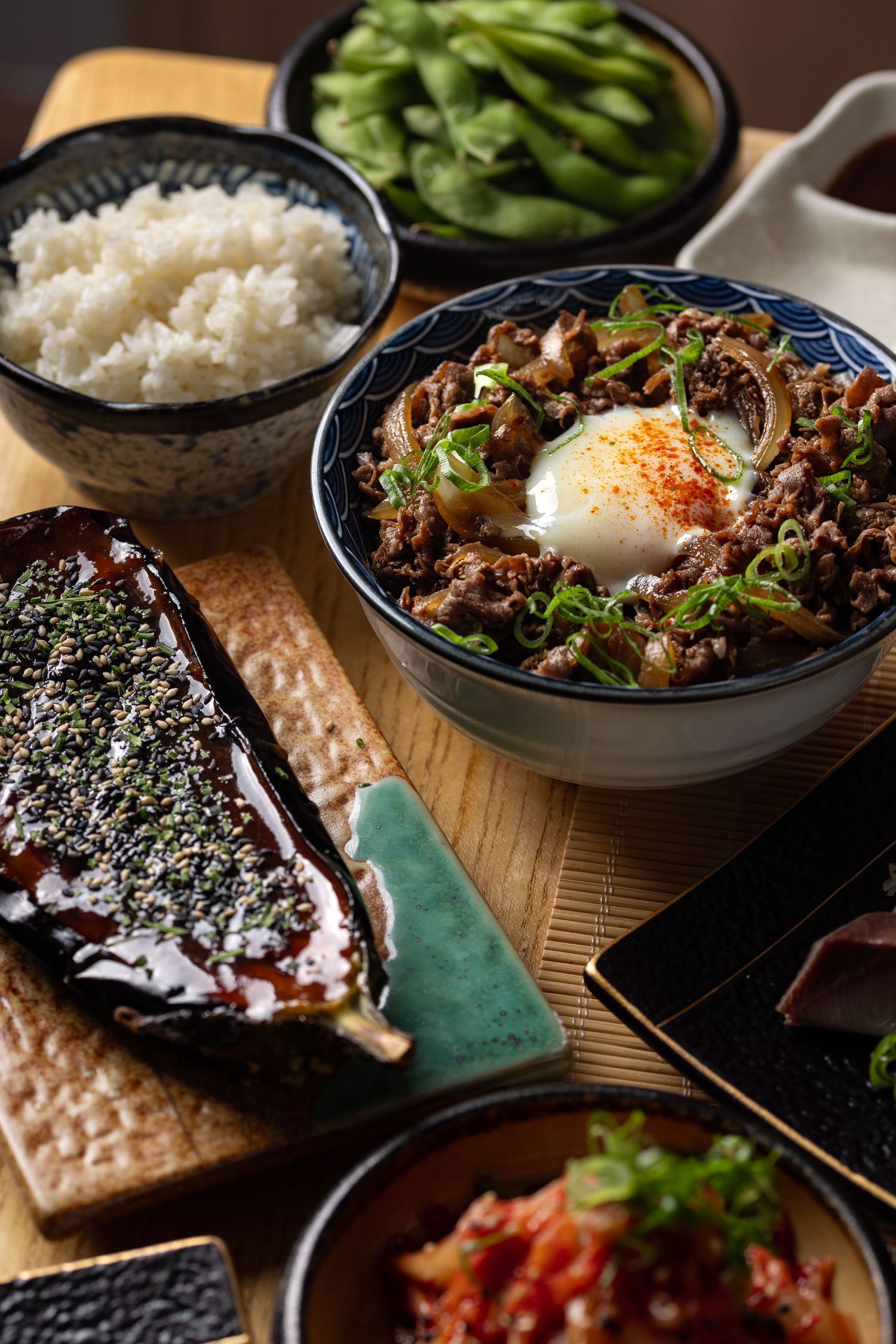 Japanese gyudon beef bowl with soft-boiled egg, edamame, rice, teriyaki aubergine and kimchi at Roppongi restaurant, Japanese food photography Southampton