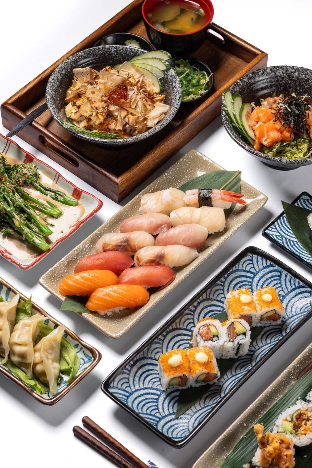 Japanese sushi and sashimi spread with nigiri, maki rolls, ramen and gyoza on a white background at Konjiki Kensington London, menu food photography