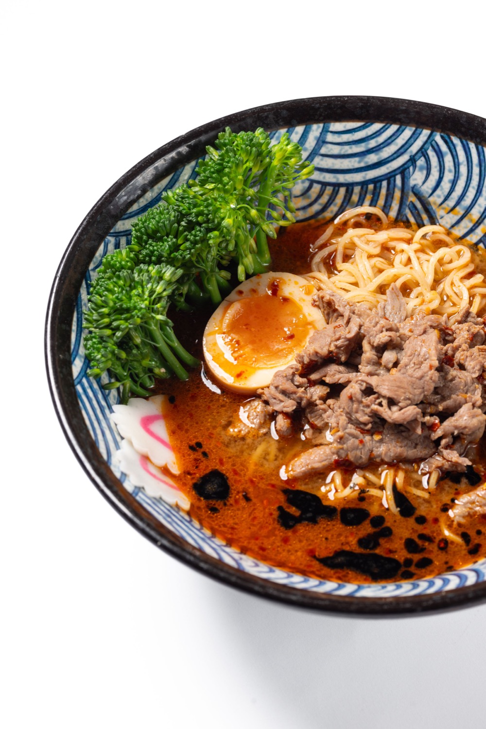 Beef ramen with soft-boiled egg, tenderstem broccoli and narutomaki in a rich broth at Konjiki Kensington London, Japanese food photography