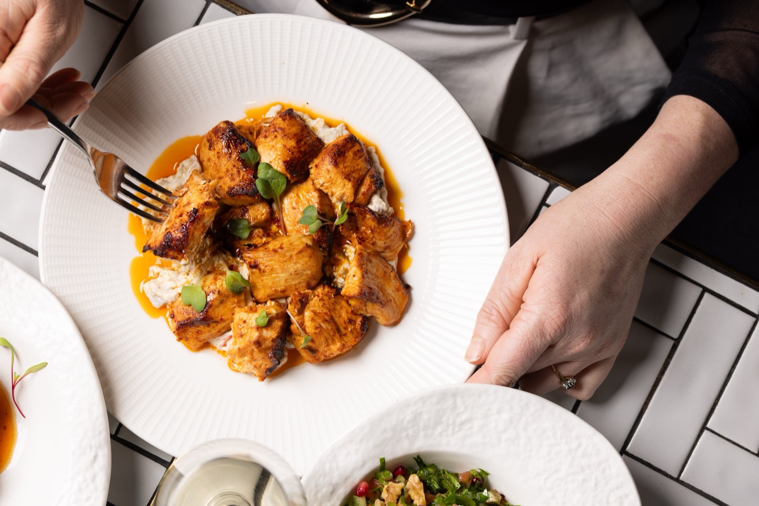 Charcoal-grilled chicken skewer with micro herbs on a white ridged plate served on white metro tiles at The Mantl Knightsbridge, Turkish food photography London