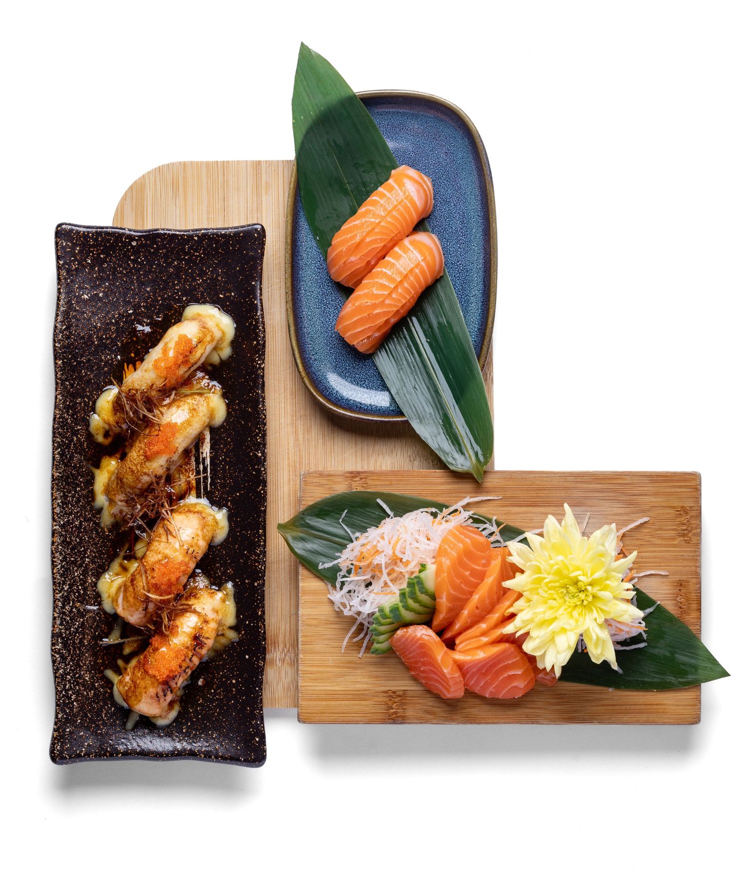 Japanese salmon sashimi, salmon nigiri and torched nigiri on bamboo leaves and wooden boards at Sakura Portsmouth, Japanese food photography