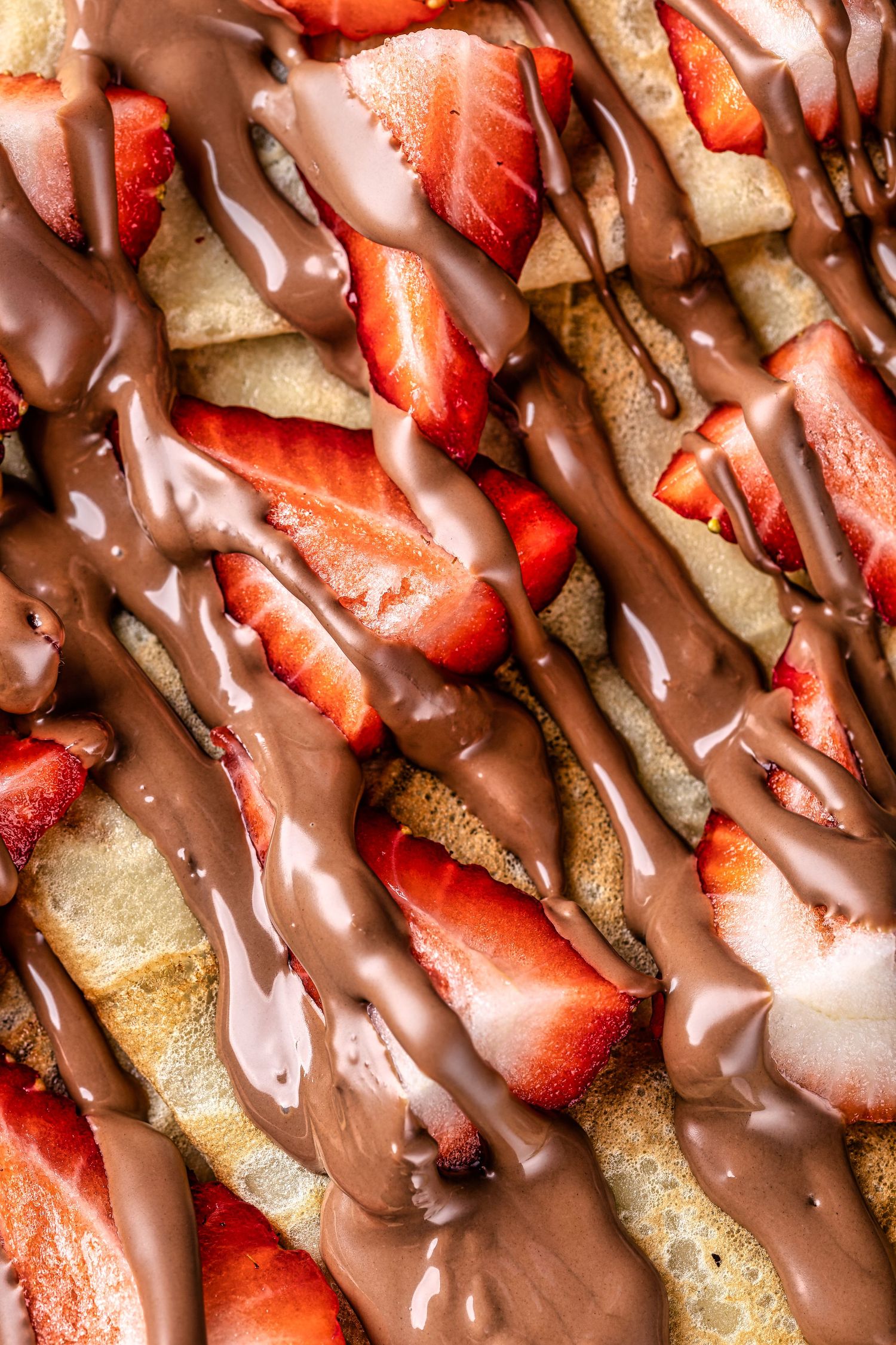 Close-up of crepe strips topped with fresh strawberry slices and drizzled with milk chocolate at Sprinkles dessert shop, dessert food photography