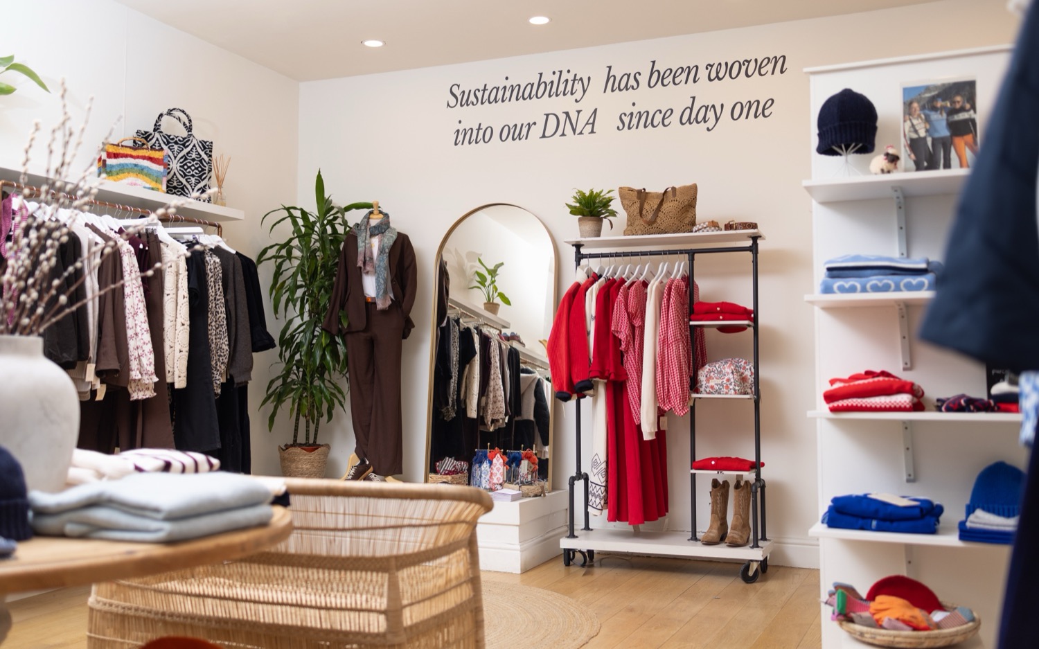 Aspiga sustainable fashion boutique interior with clothing rails, arched mirror, houseplants and sustainability wall quote at Kings Road London, retail interior photography