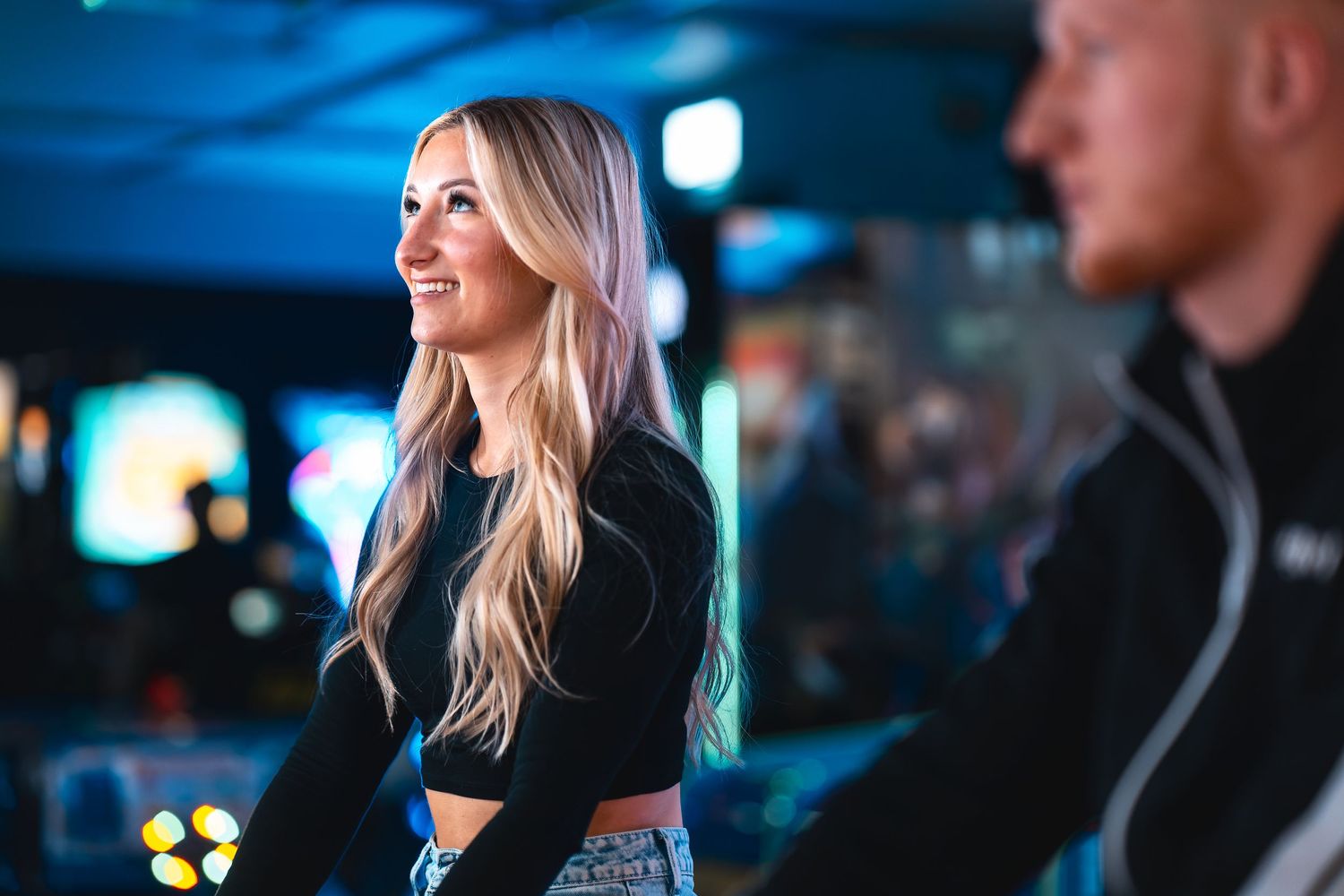 Woman smiling at an arcade entertainment venue with blue neon lighting, leisure lifestyle photography Southampton