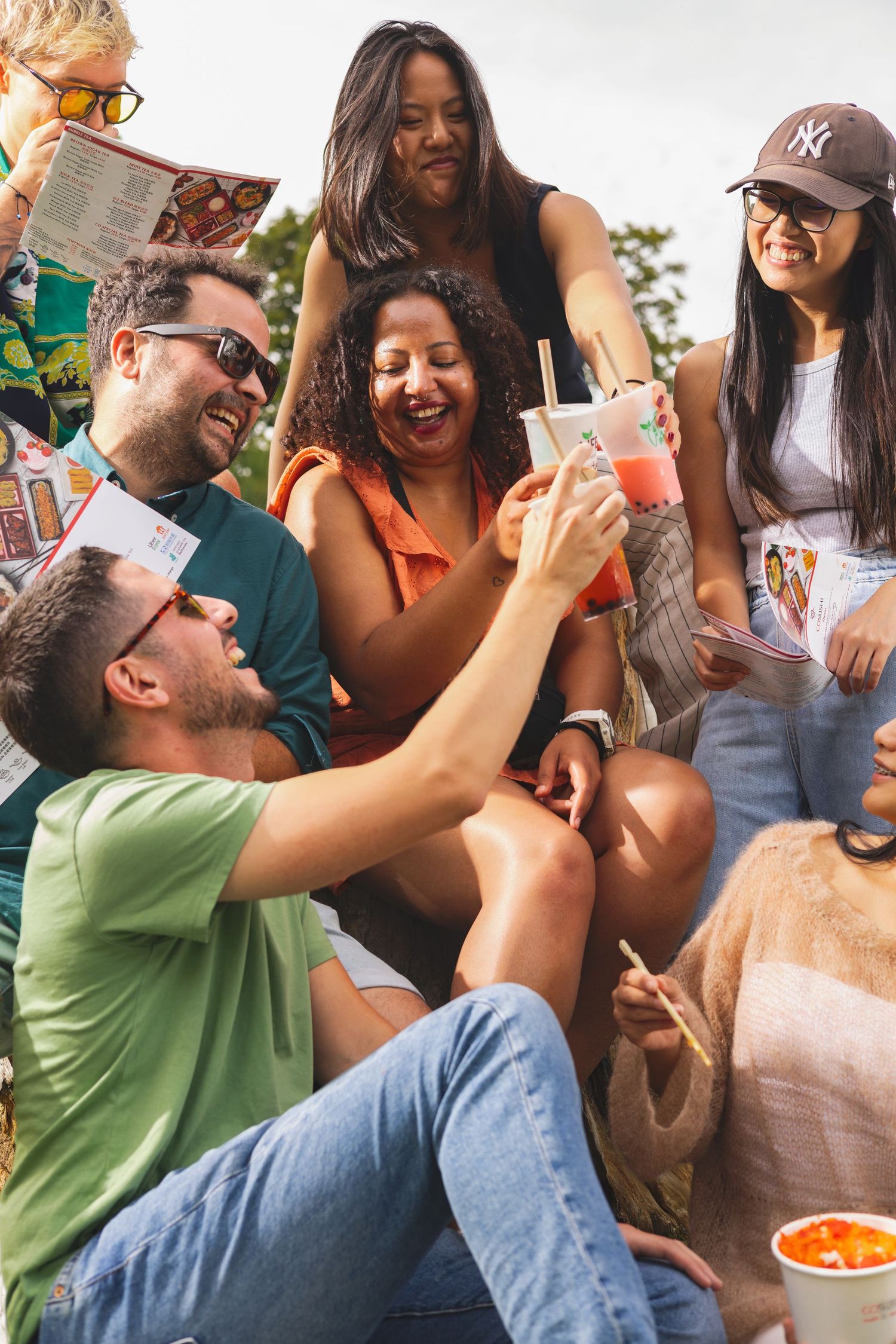 Group of friends laughing and toasting drinks outdoors at a Co-Sushi event Southampton, candid social lifestyle photography