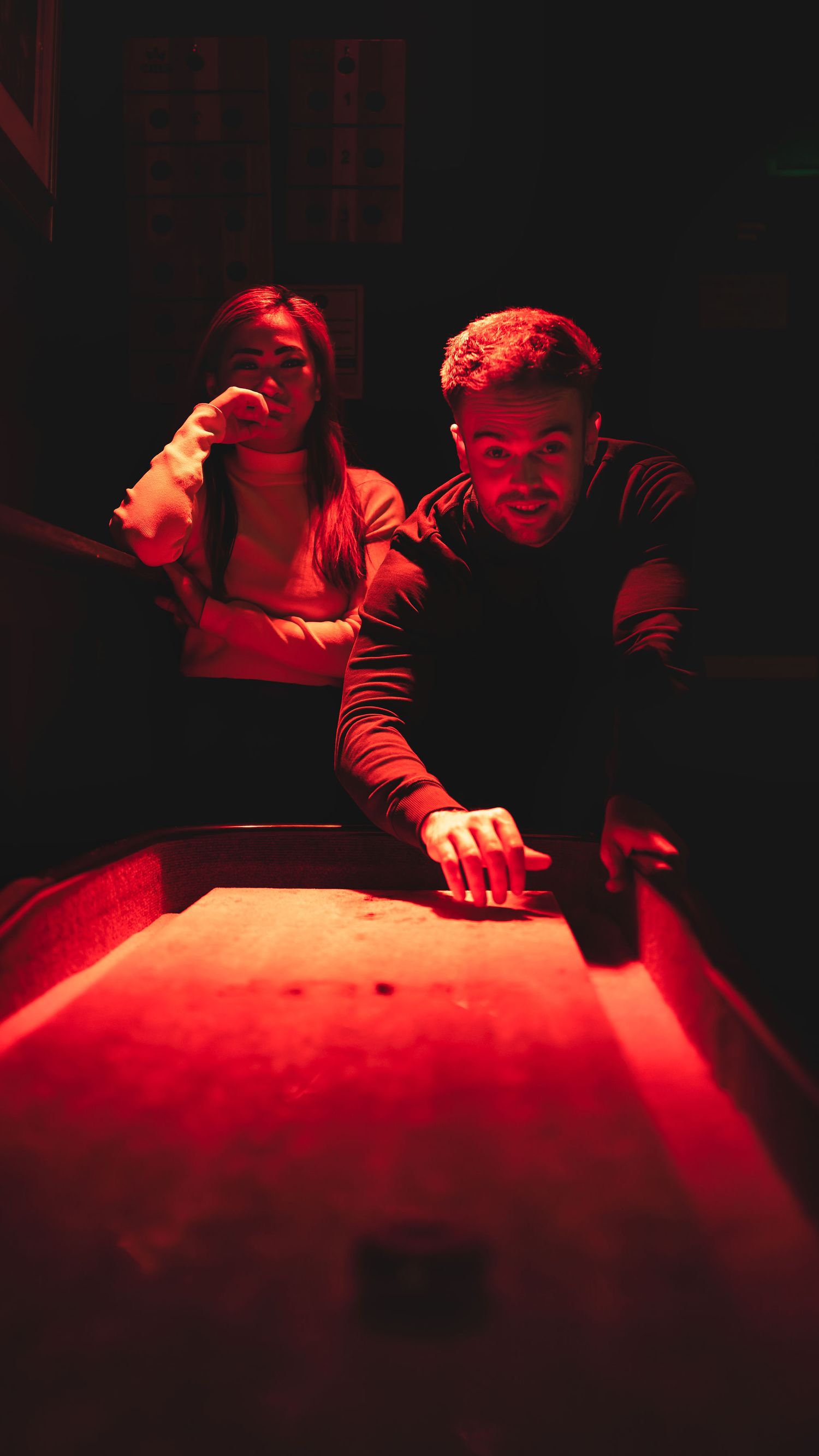 Two friends playing pool in dramatic red lighting at a bar, nightlife lifestyle photography Southampton