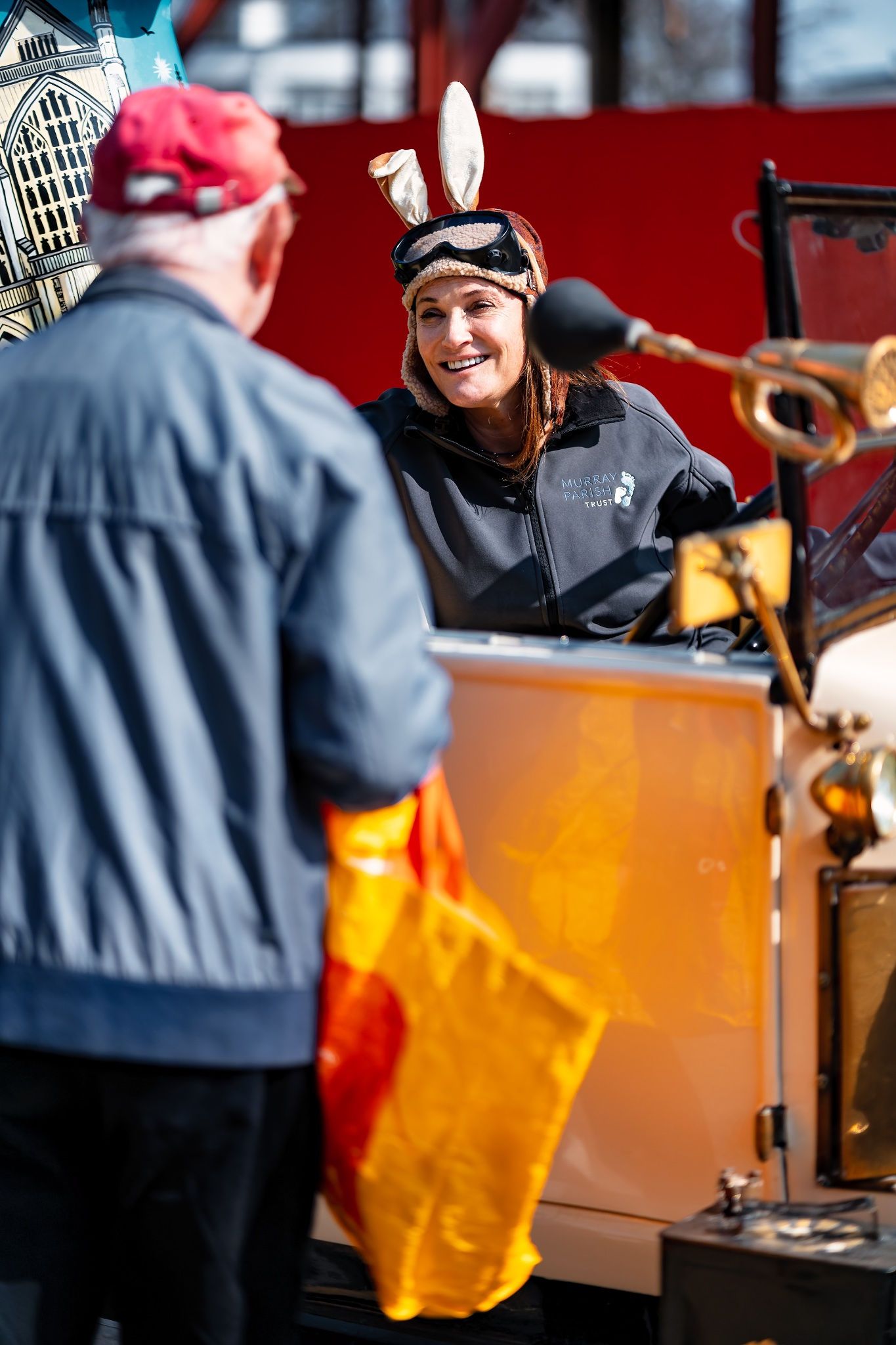 Woman in bunny ears smiling on a vintage car float at a community parade for Murray Parish Trust, event lifestyle photography Southampton