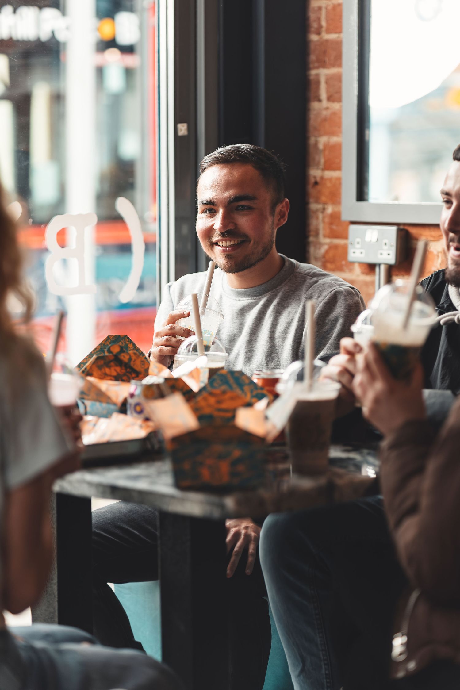 Friends enjoying milkshakes and burgers at a restaurant table by the window, candid dining lifestyle photography Southampton