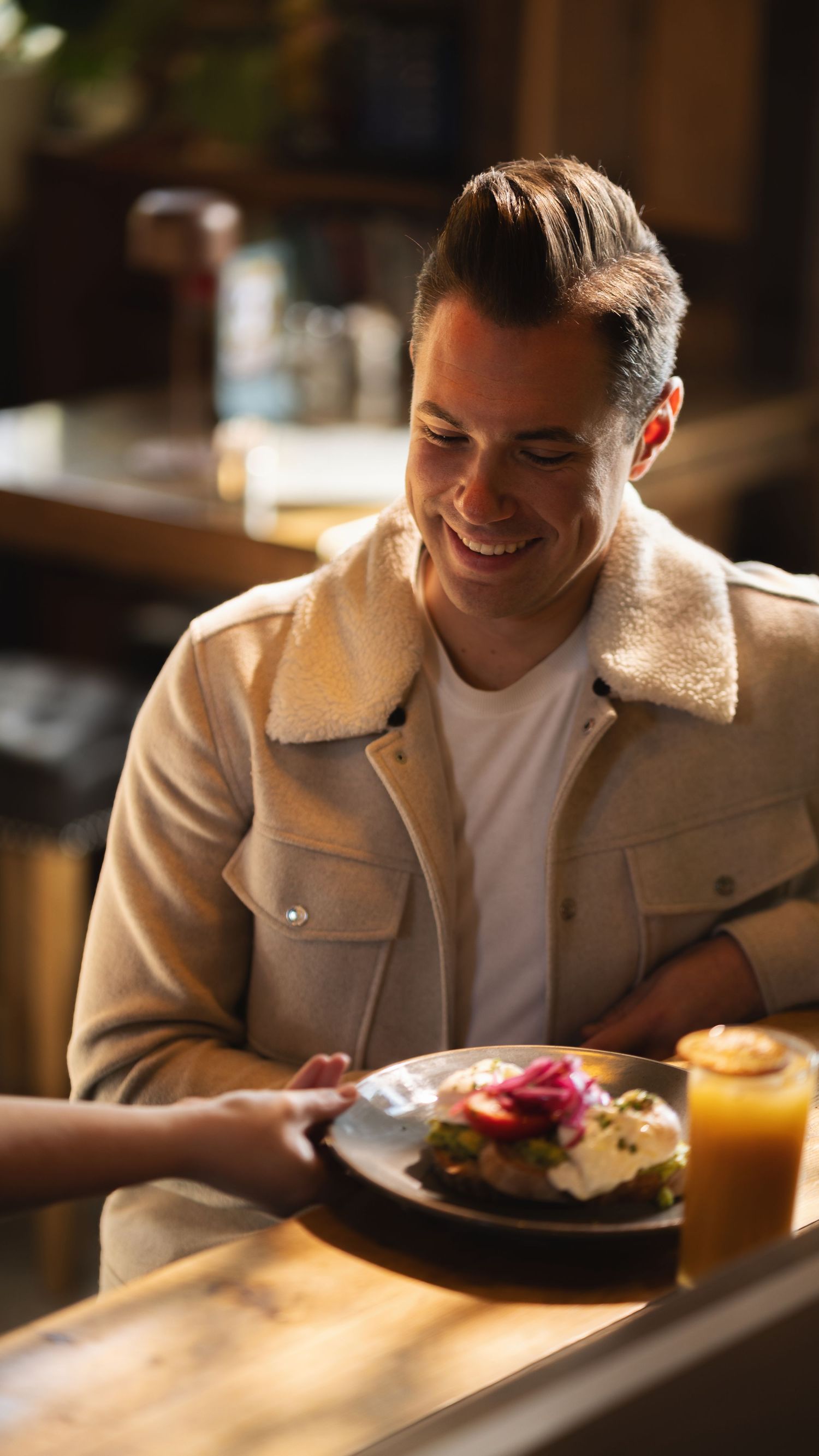 Man smiling as brunch is served to his table at Mettricks Portswood cafe Southampton, hospitality lifestyle photography