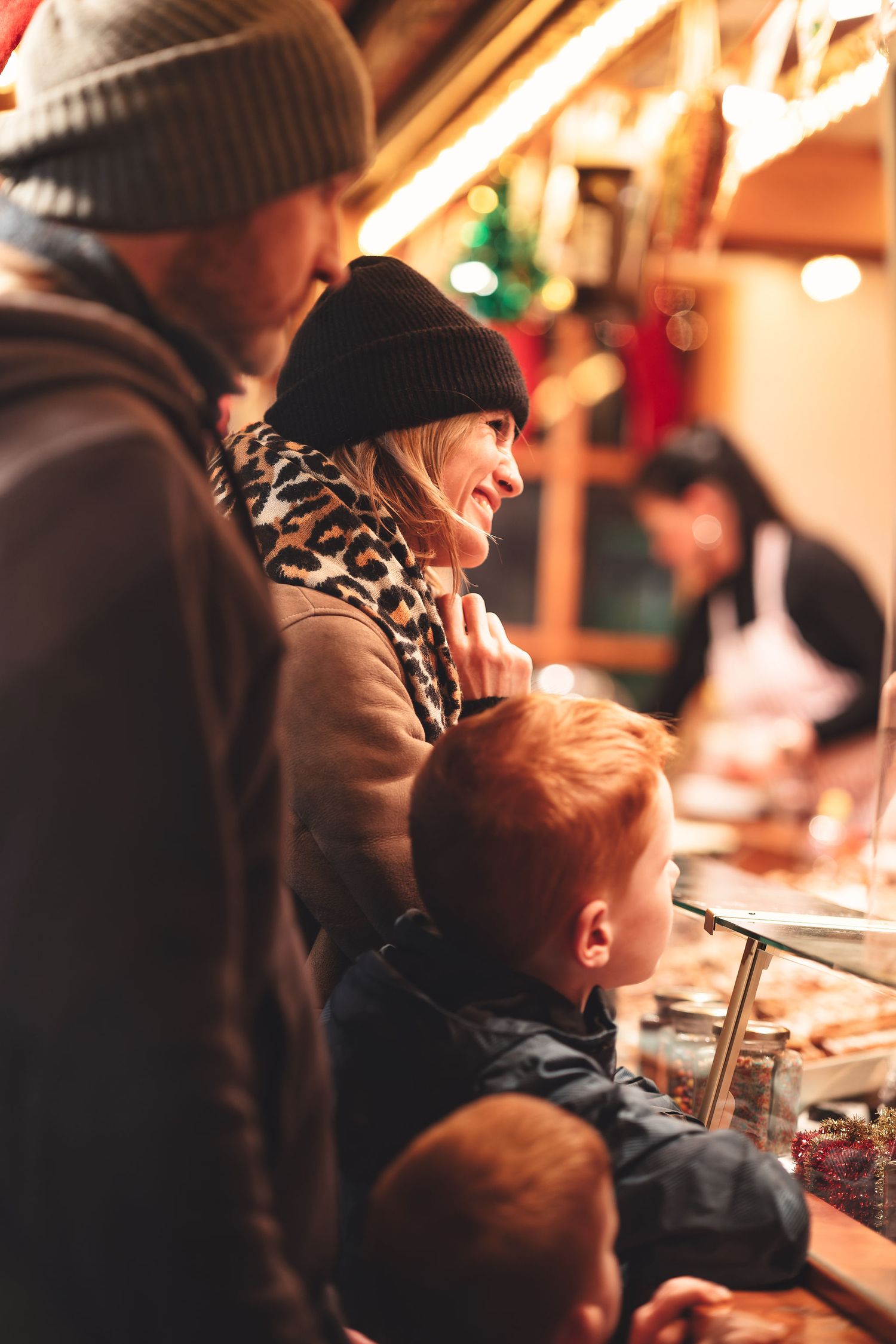 Family browsing a Christmas market stall with warm festive lighting, holiday lifestyle photography Southampton