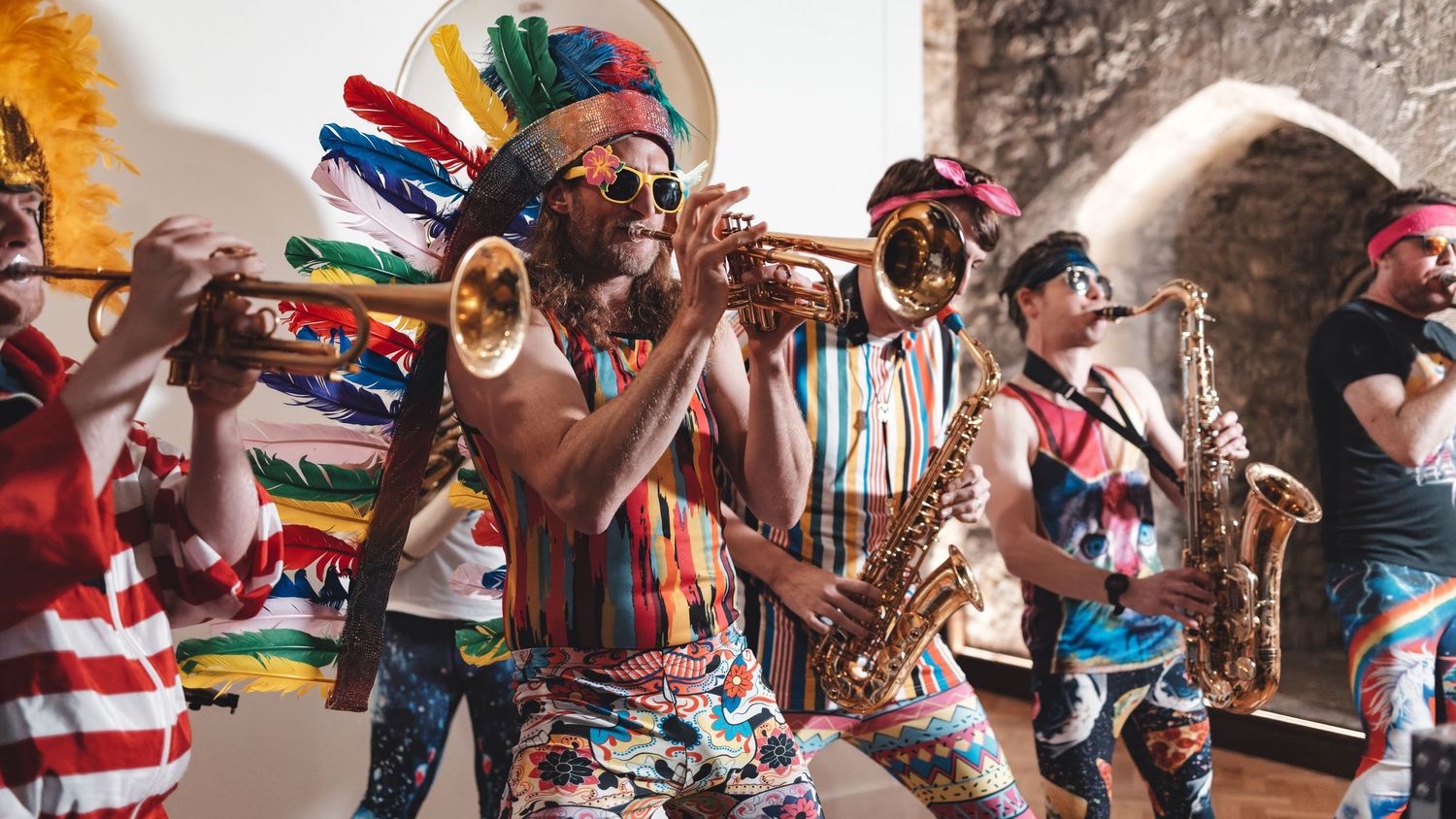 Brass band with trumpets and saxophones performing in colourful outfits at an indoor venue, live music event photography