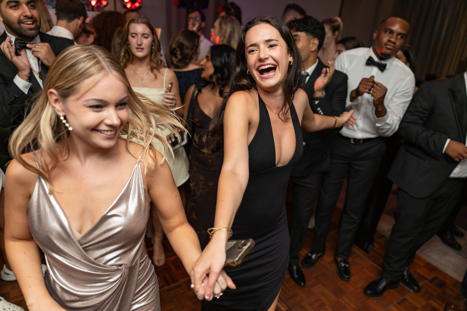 Guests in evening dresses laughing on the dance floor at the University of Southampton MedSoc graduation ball, Novotel Southampton event photography