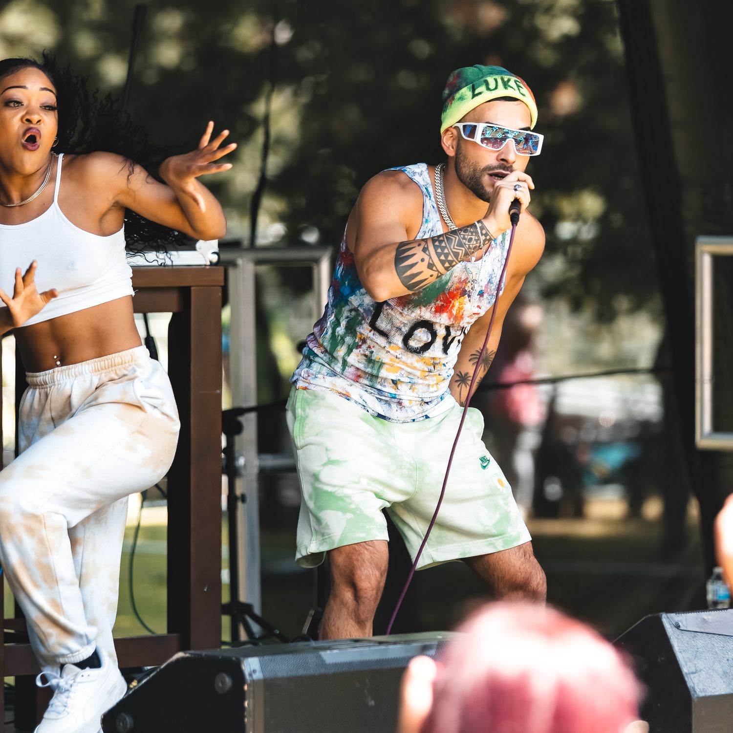 MC with microphone and dancer performing on an outdoor stage at Party in the Park in summer sunshine, live music event photography Southampton
