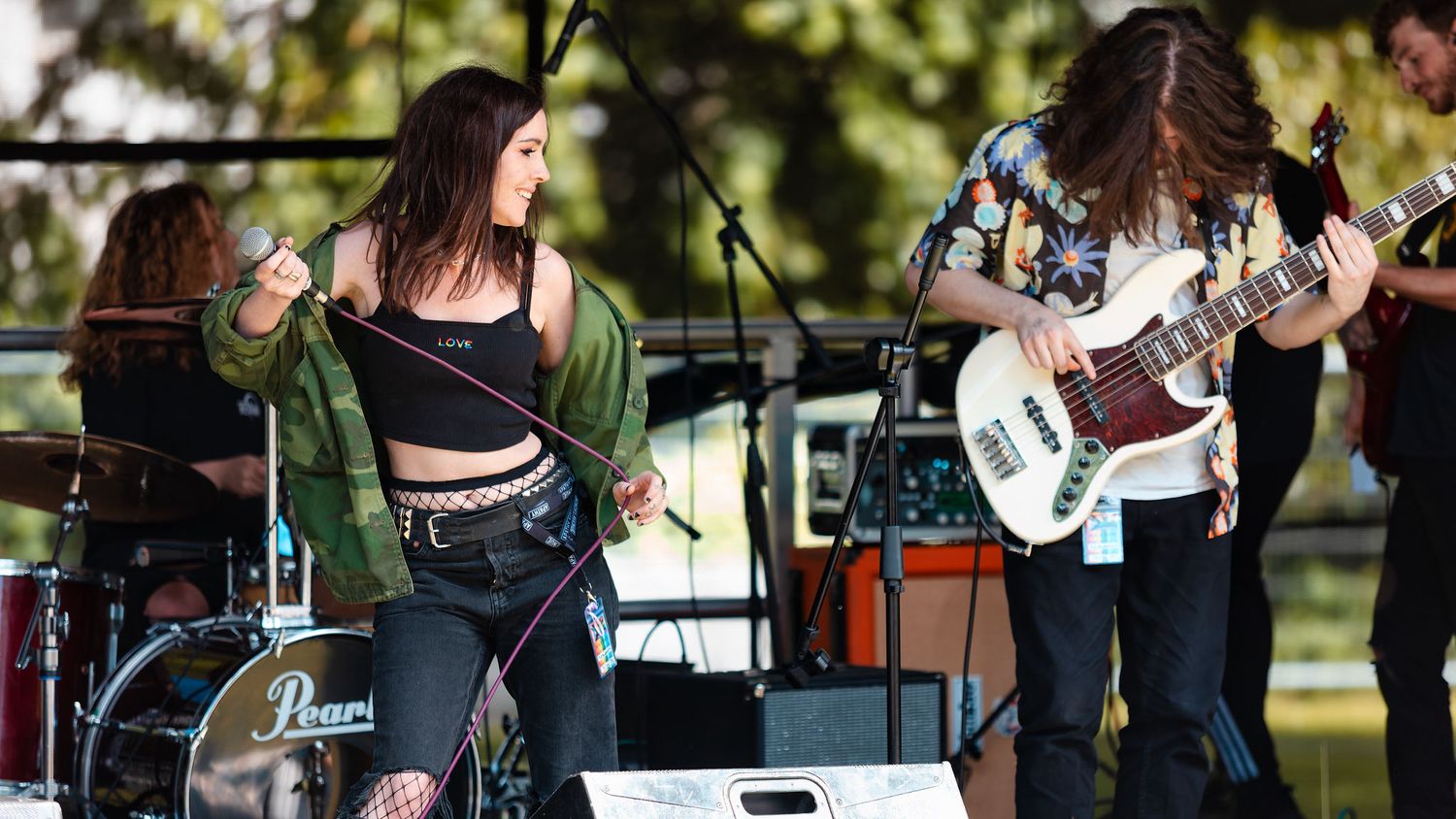 Female singer with microphone and male bassist performing on an outdoor festival stage at Southampton Pride, live music festival photography
