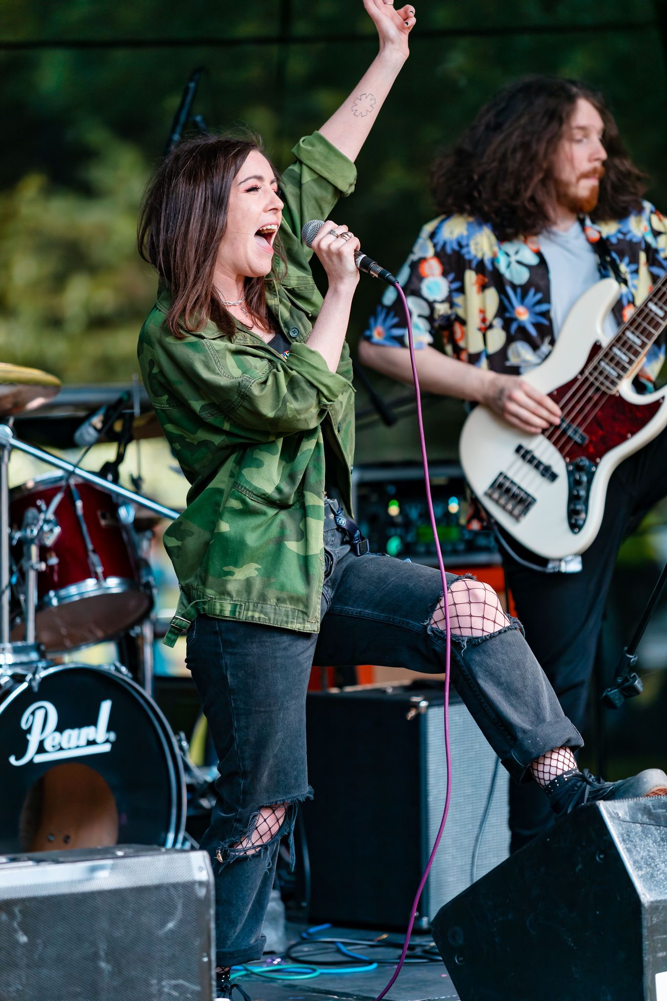 Singer and bassist performing together on an outdoor festival stage at Southampton Pride with Pearl drums behind, live music event photography
