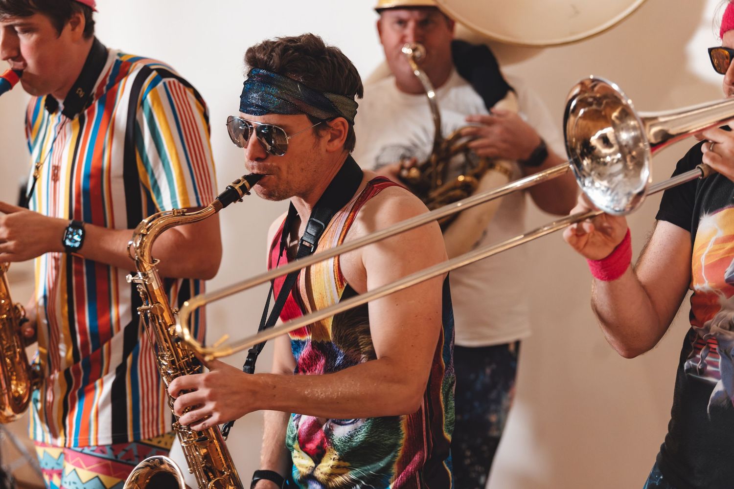 Brass band saxophonist and trombonist performing in colourful outfits at an indoor venue, live music event photography Southampton