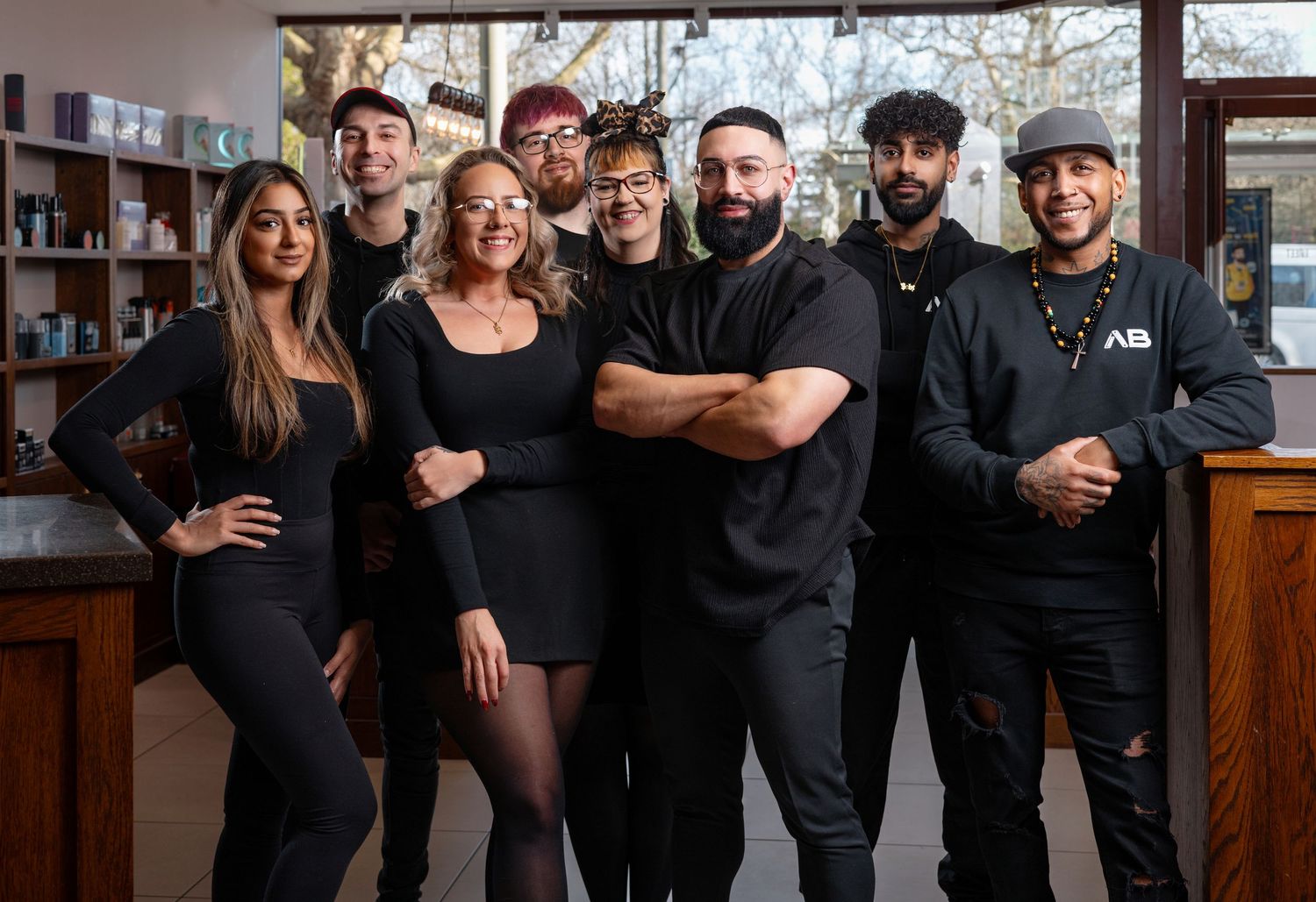 Team of eight staff dressed in black posing together in a modern interior, corporate team headshot photography