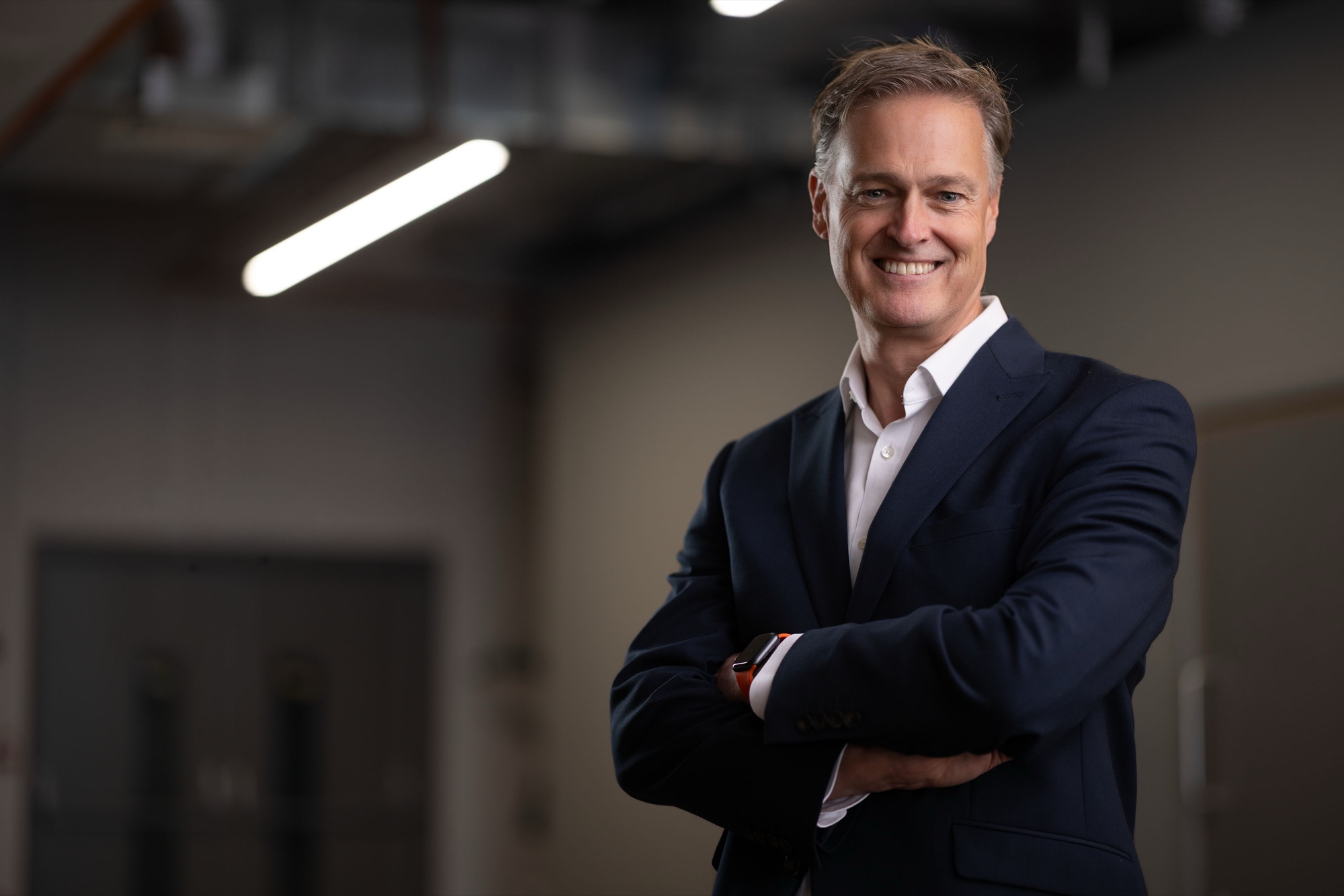 Chair of the Go Southampton board of directors smiling in a navy suit with arms crossed in a modern office, corporate headshot photography