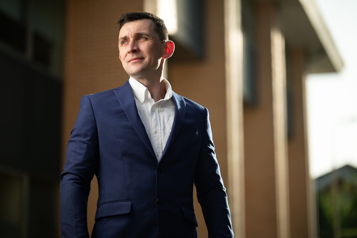 Man in a navy suit and open collar looking off camera in golden evening light at Ocean Village, Southampton personal branding portrait photography