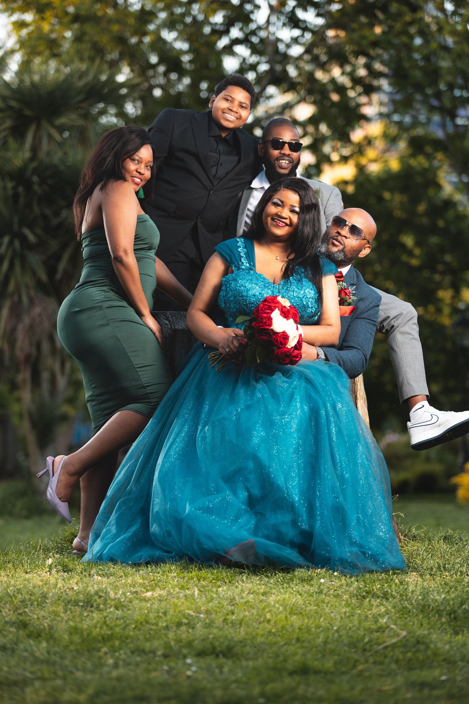 Masego in a turquoise ball gown holding a red bouquet with family gathered around her on a garden lawn, group portrait photography Southampton