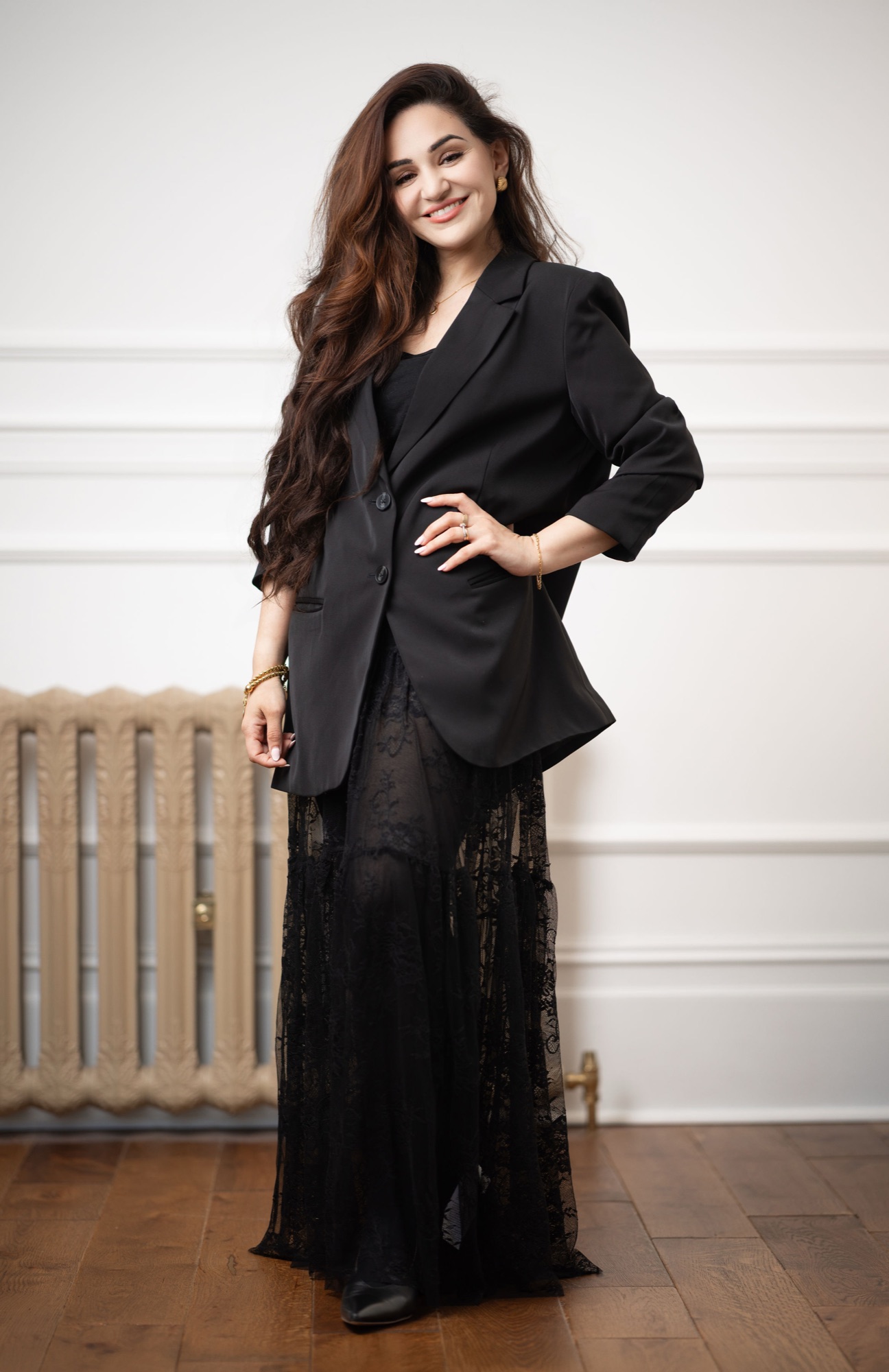 Shamma in a black blazer and sheer lace maxi dress, hand on hip, smiling in an elegant panelled room, personal portrait photography Southampton