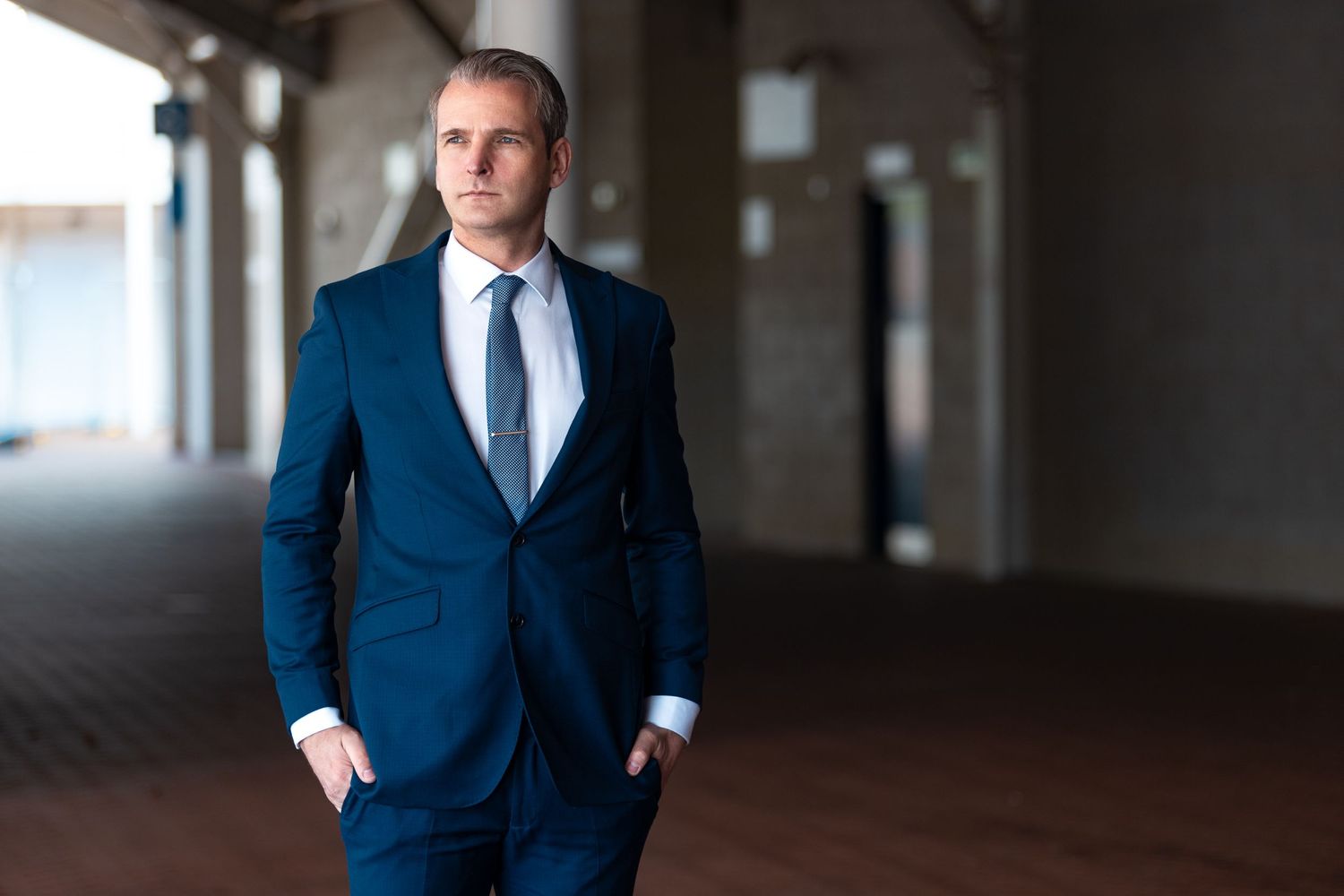 Steven Exley in a navy blue suit with white shirt and tie standing in a covered walkway, professional business portrait photography Southampton
