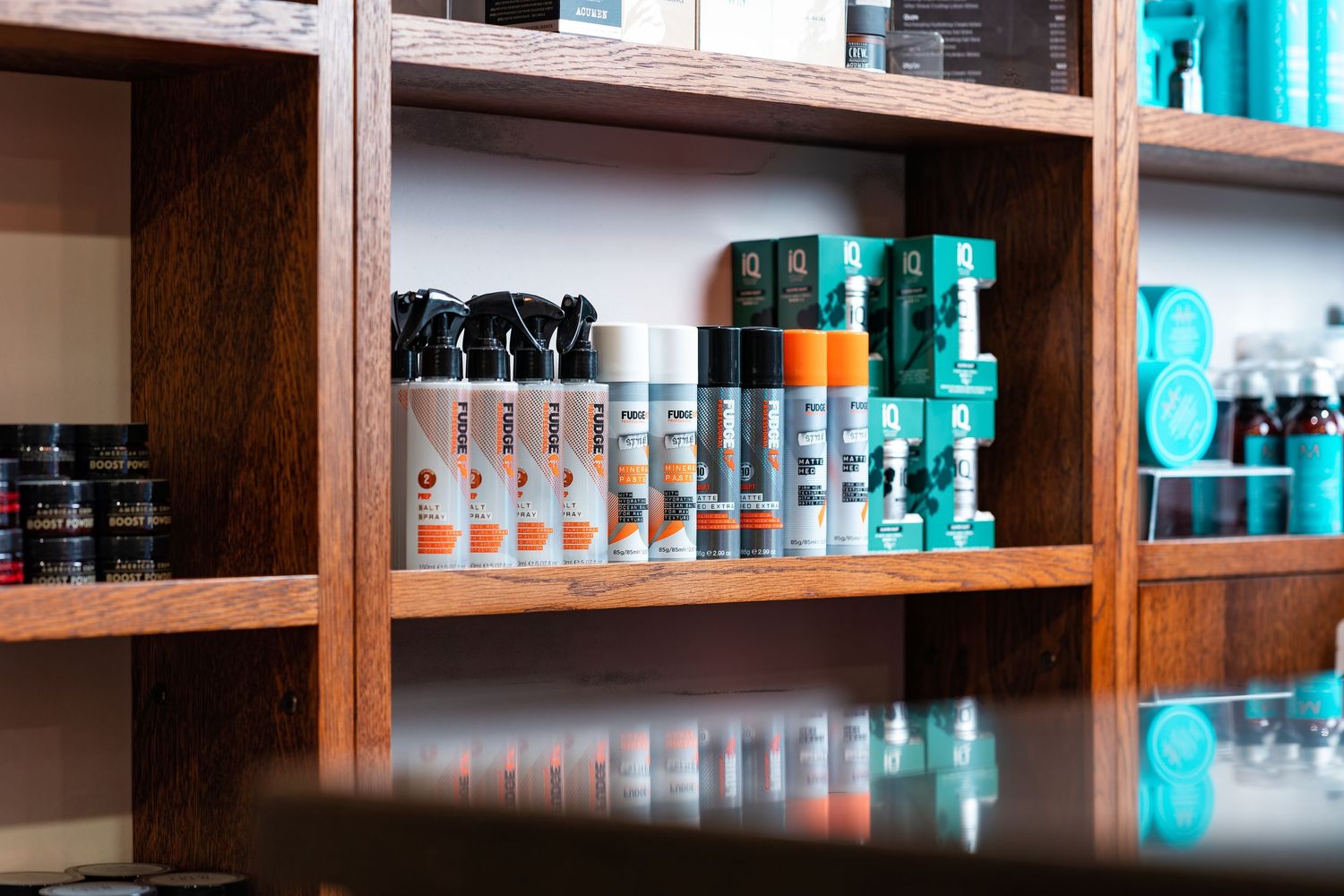 Fudge and IQ haircare products lined up on wooden shelves at Above Barbers salon Southampton, barber product photography