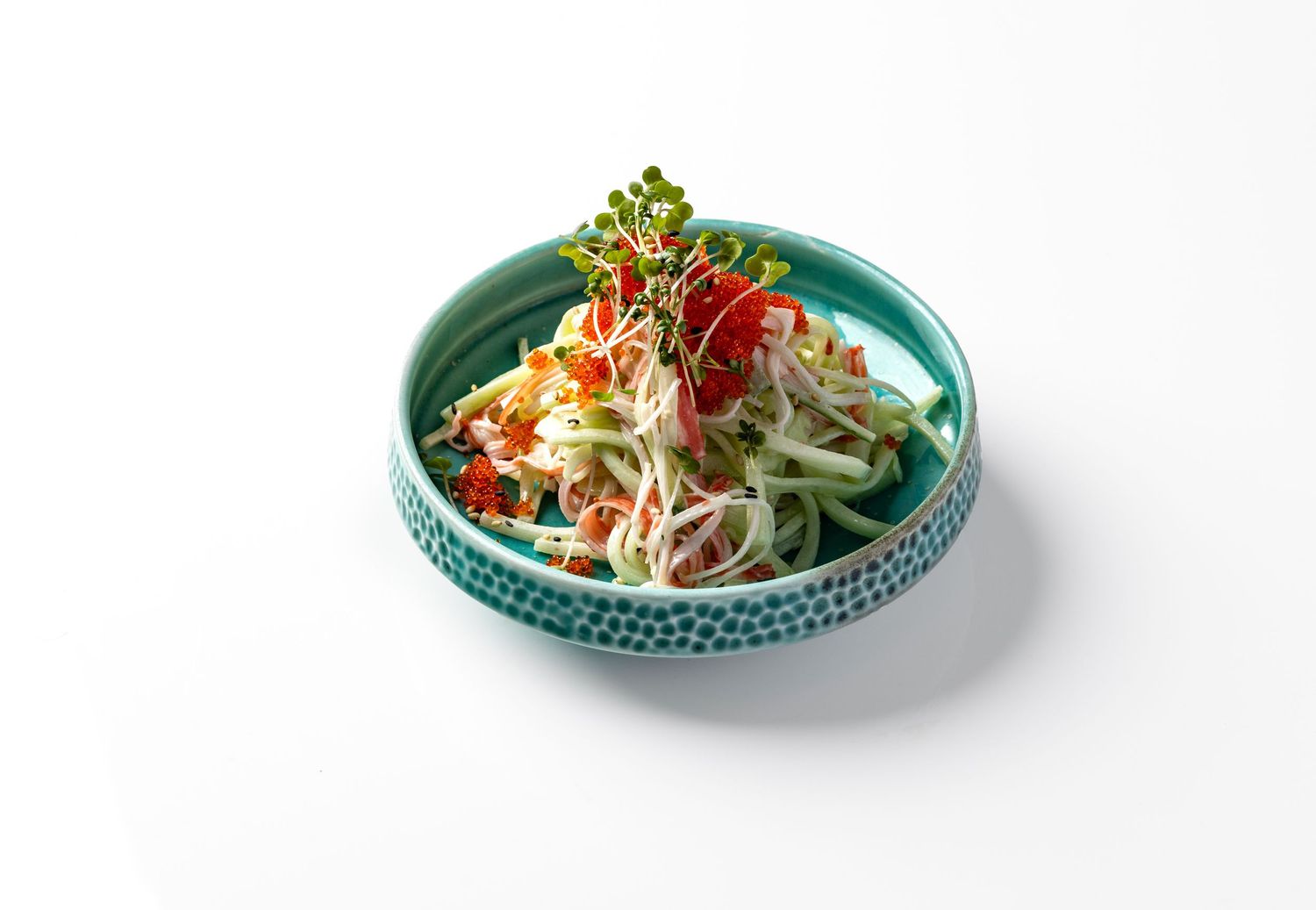 Japanese crab and cucumber salad with tobiko roe and microgreens in a teal ceramic bowl on a white surface for Roppongi restaurant, food product styling photography