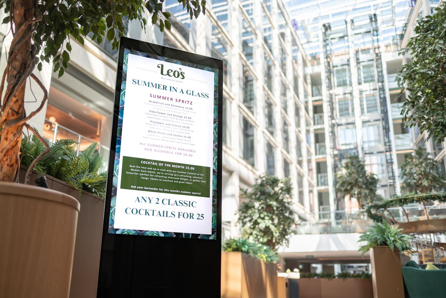 TrouDigital freestanding digital menu board displaying cocktail offers at Leo\